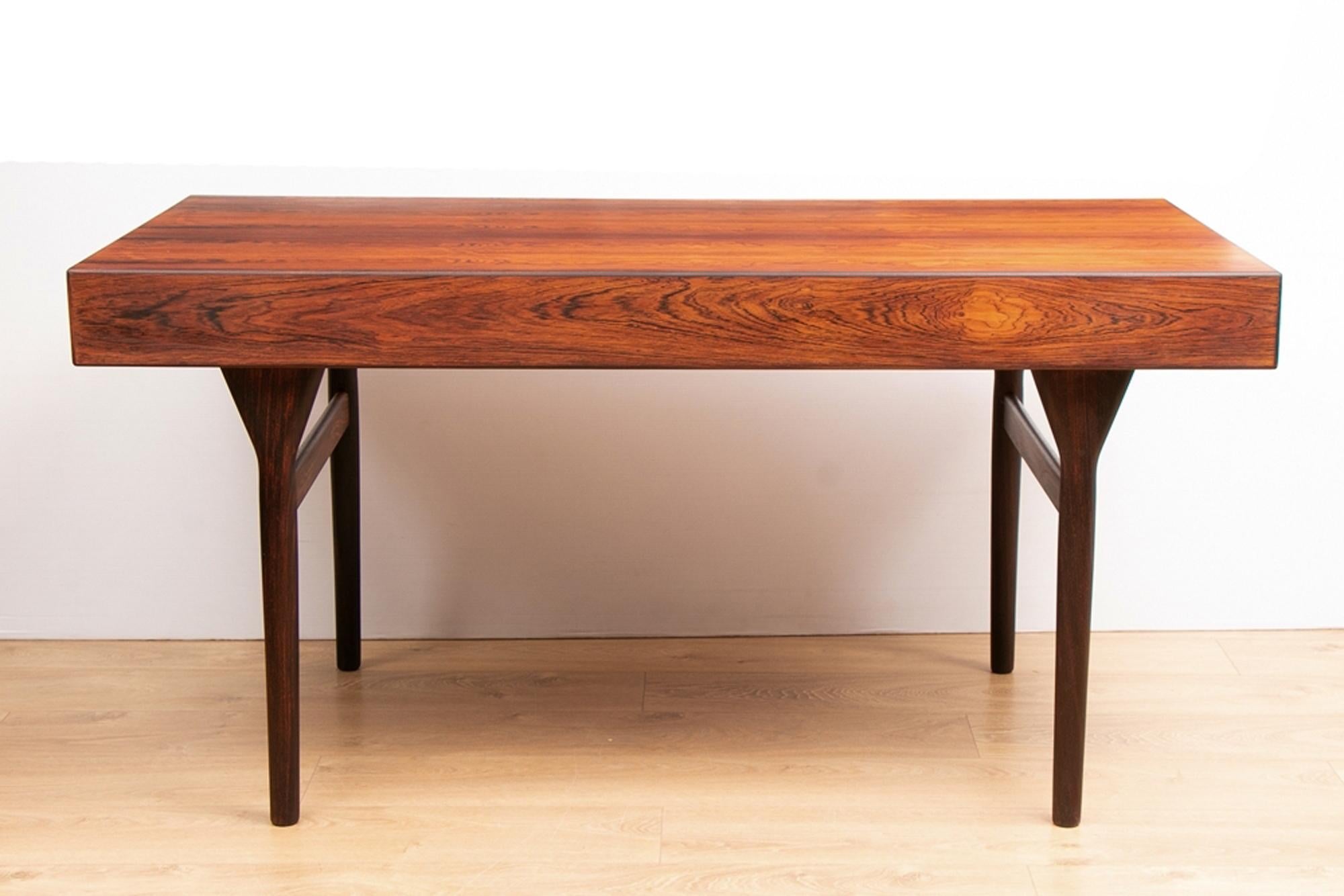 Nanna Ditzel. Freestanding rosewood desk , front with three drawers with integrated grips, tapered legs. Designed in 1958. Produced by Søren Willadsen, Vejen. This desk is in superb original condition with outstanding rosewood veneers and made to