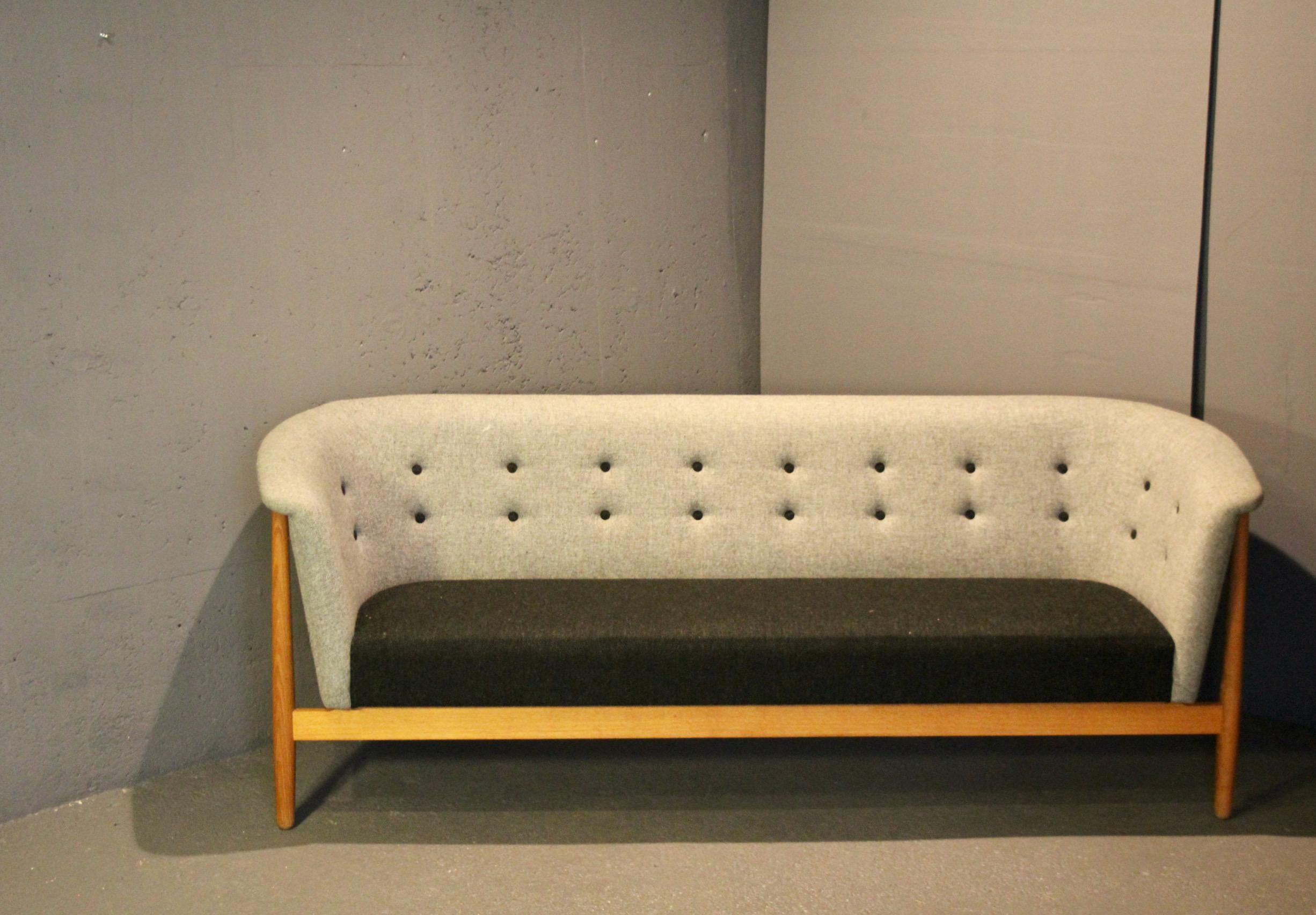 Progettato da Nanna and Jørgen Ditzel negli anni '50, questo splendido modello è conosciuto come il divano Vita. La Silhouette si ispira alle forme tradizionali ma è realizzata con un design aperto e organico. Tessuti a contrasto e bottoni a