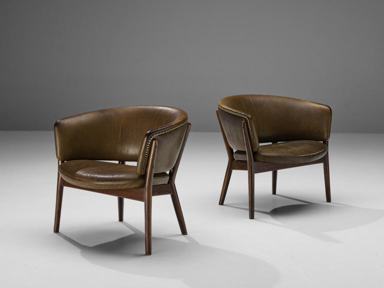 Nanna Ditzel for Soren Willadsen, easy chairs model 'ND83', beech, original leather, Denmark, 1952.

Set of two round lounge chairs with a dark stained wooden frame and olive green leather upholstery. The wooden frame is beautifully shaped and gives