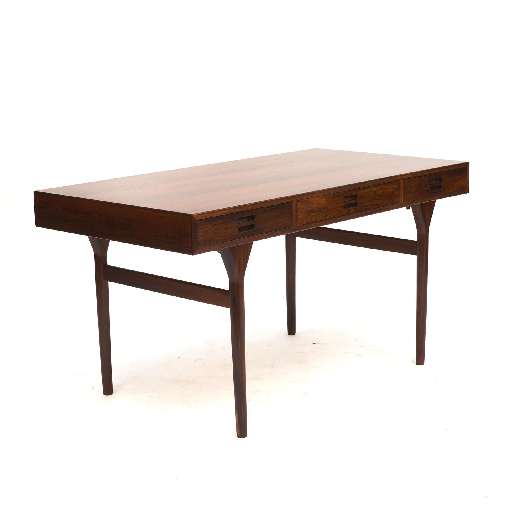 Nanna Ditzel. Freestanding rosewood veneered desk.
Desk, apron and legs with a magnificent grain. Front with three drawers with integrated grips. Tapered legs.

Designed in 1958. Produced by Søren Willadsen, Vejen.
This desk is in superb