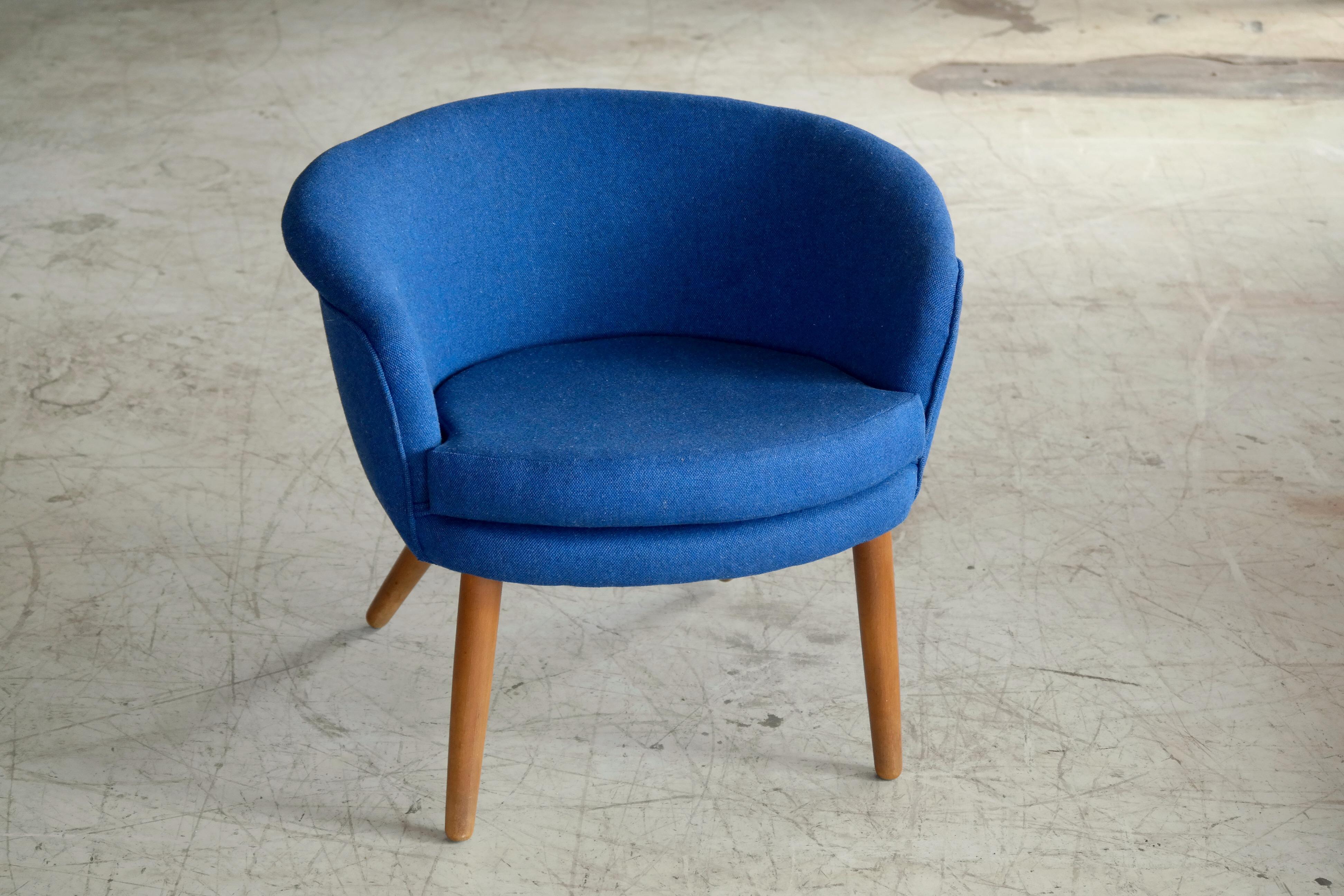 Charming easy chair made in Denmark in the 1950s. Newly re-upholstered in blue wool fabric by Camira and raised on legs of solid oak. Low and light design with a lot of versatility. Unknown Producer and Designer but reminiscent of Nanna Ditzel's