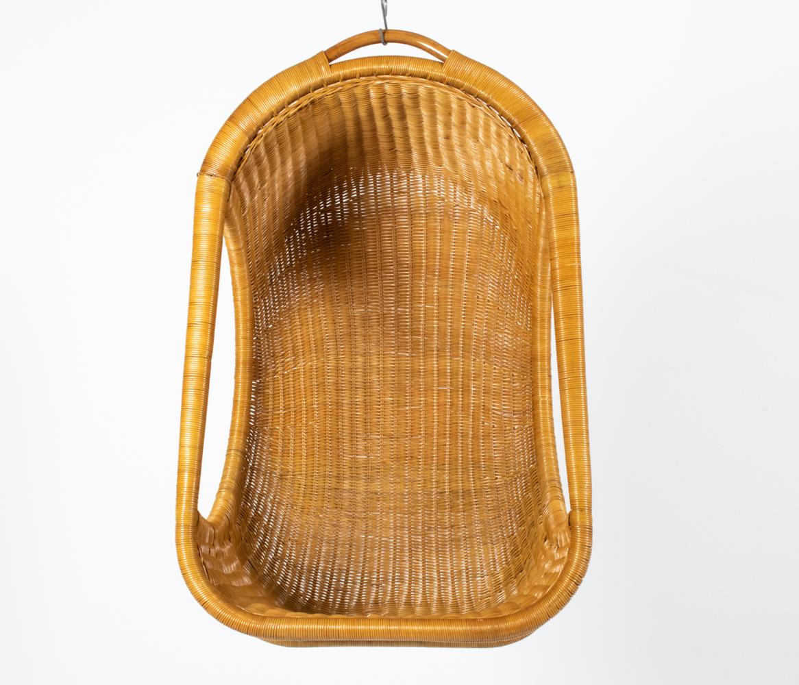 Step into a realm of timeless design and comfort with this Nanna Ditzel-Style Mid-Century Hanging Rattan Egg Chair. Suspended in air, its iconic cocoon shape beckons you to float away from the world and embrace serenity. Handcrafted with meticulous