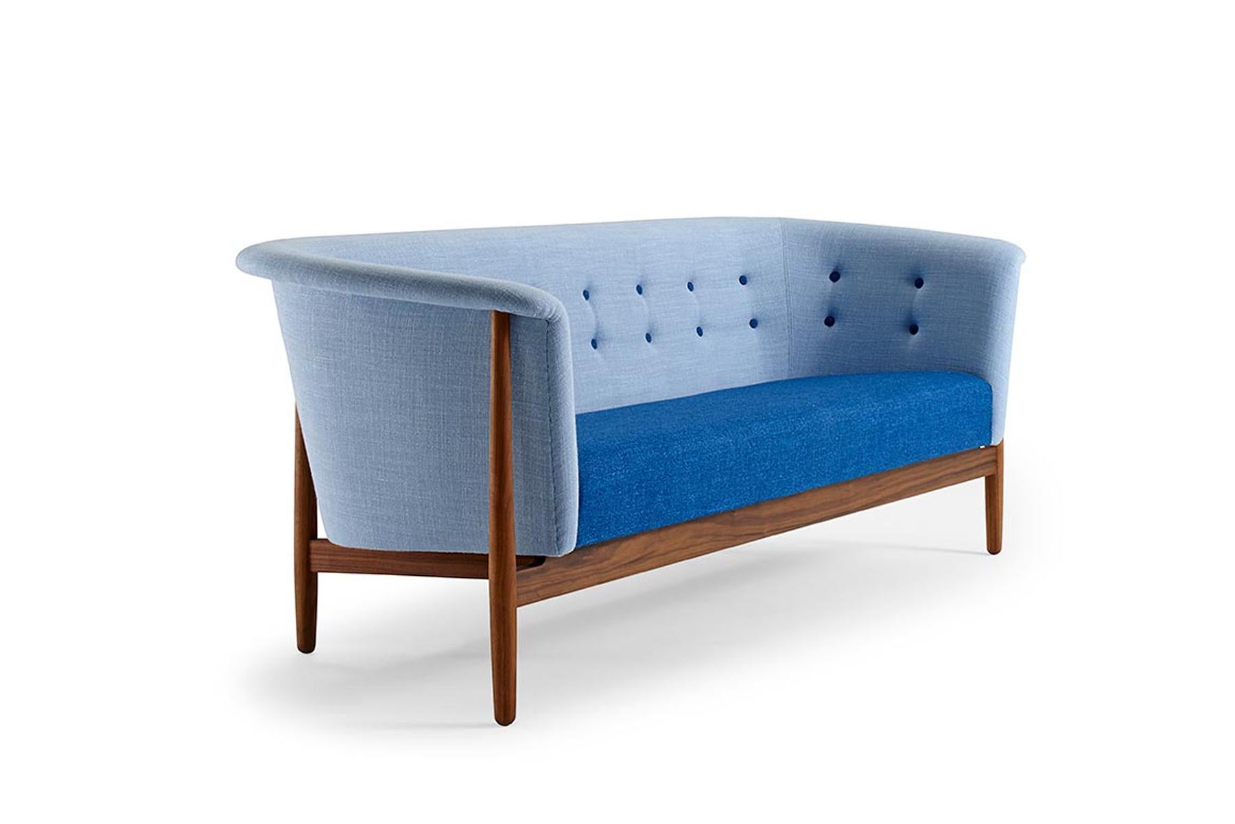 Designed by Nanna + Jørgen Ditzel in the 1950s, this stunning model is known as the Vita sofa. The silhouette pulls from traditional forms but is crafted in an open, organic design. Contrasting fabrics and button tufting adorn the upholstery