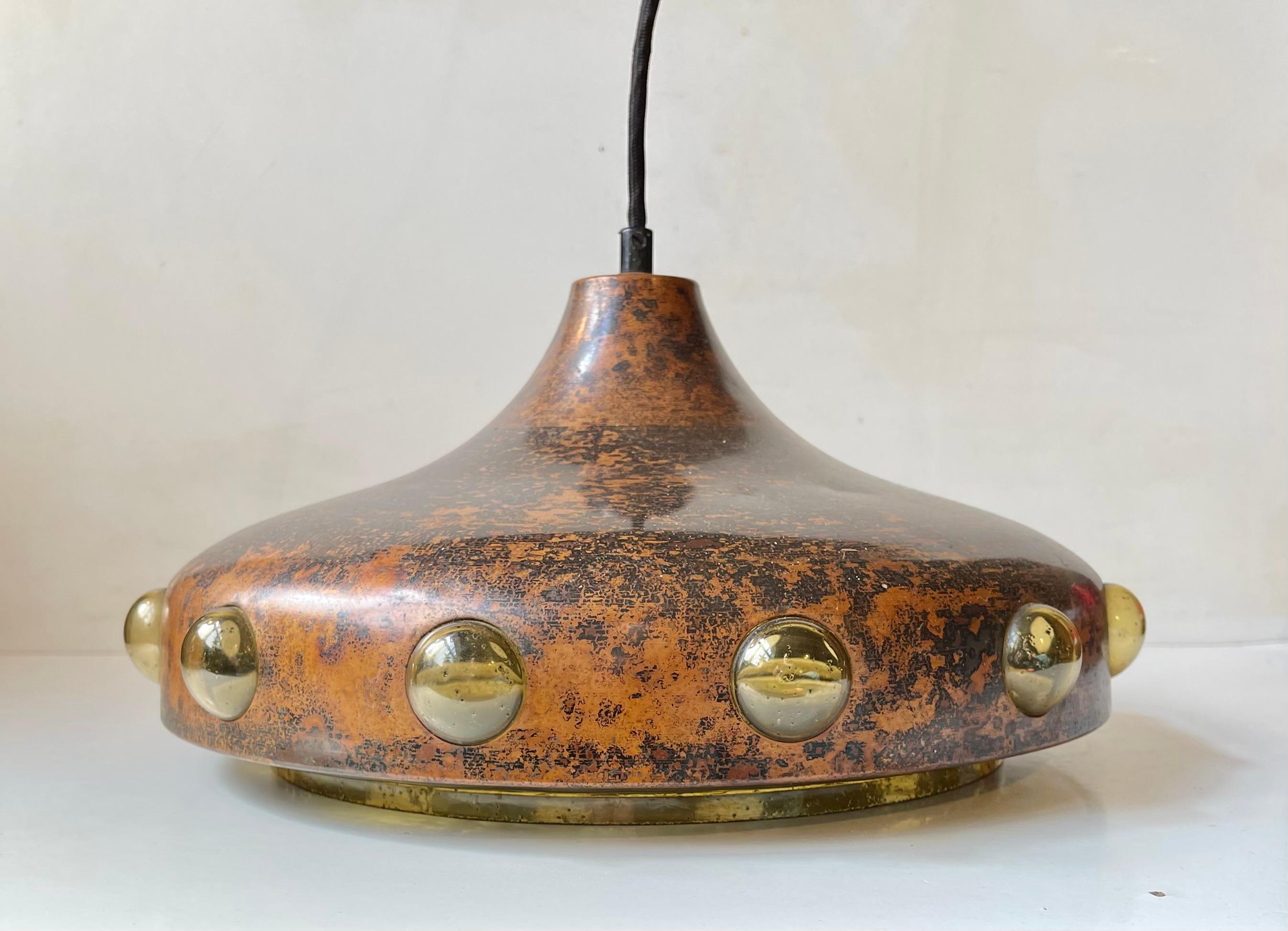 Acid-treated copper hanging pendant light with an interior textured amber glass shade with penetrating bubbles. It was designed by Finnish designer Nanny Still in the 1960s and manufactured by Raak Amsterdam. Measurements: H: 25 cm, Diameter: 32 cm.