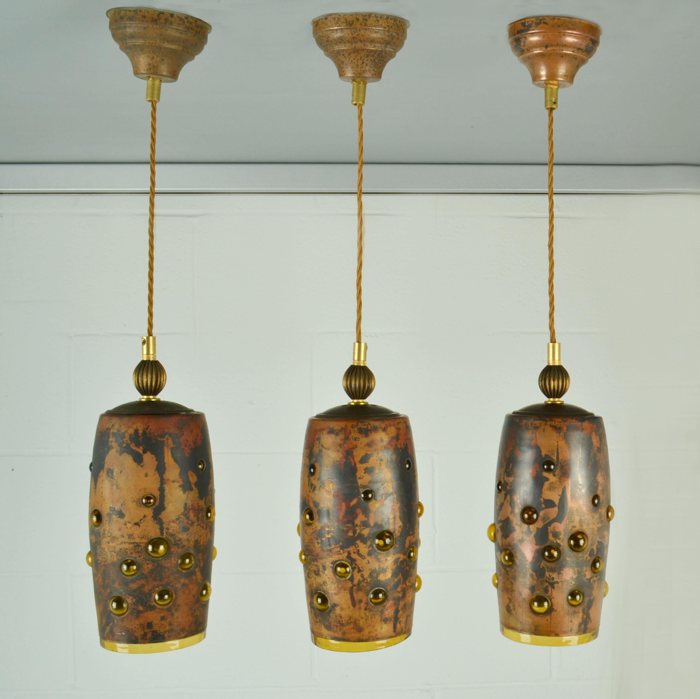 Set of Tree amber glass pendant lamps made from blown glass & oxidized copper. They are all unique in execution. The deep amber expanded glass is blown with regularity into external patinated copper spherical frames. The mix of metal and trapped