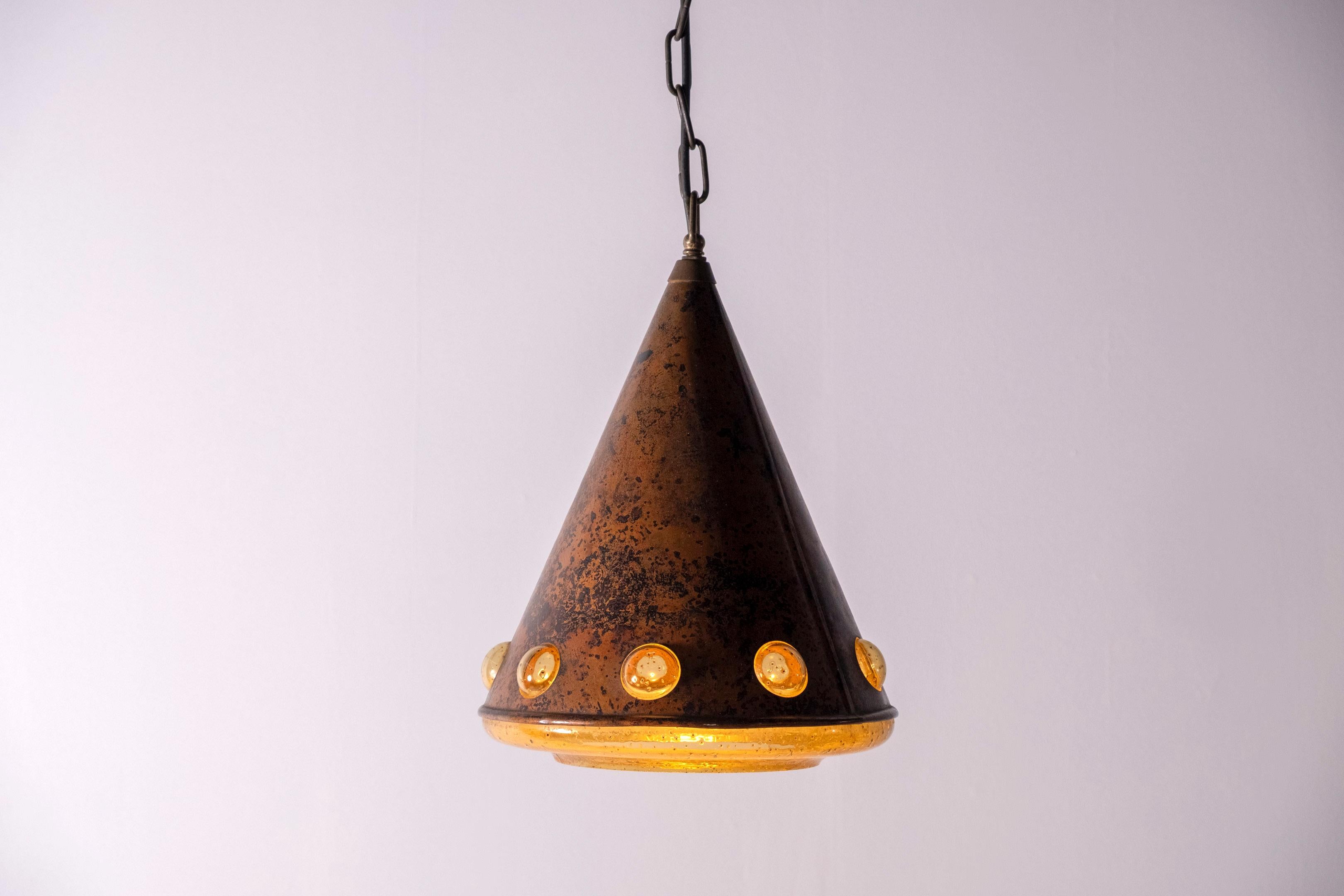 Kupferanhänger aus den 1960er Jahren von der finnischen Designerin Nanny Still McKinney für das niederländische Unternehmen RAAK. Dicker, strukturierter Braunglaskegel mit geschwärztem Kupfer überzogen. Das Licht wird durch neun Glasperlen/Augen an