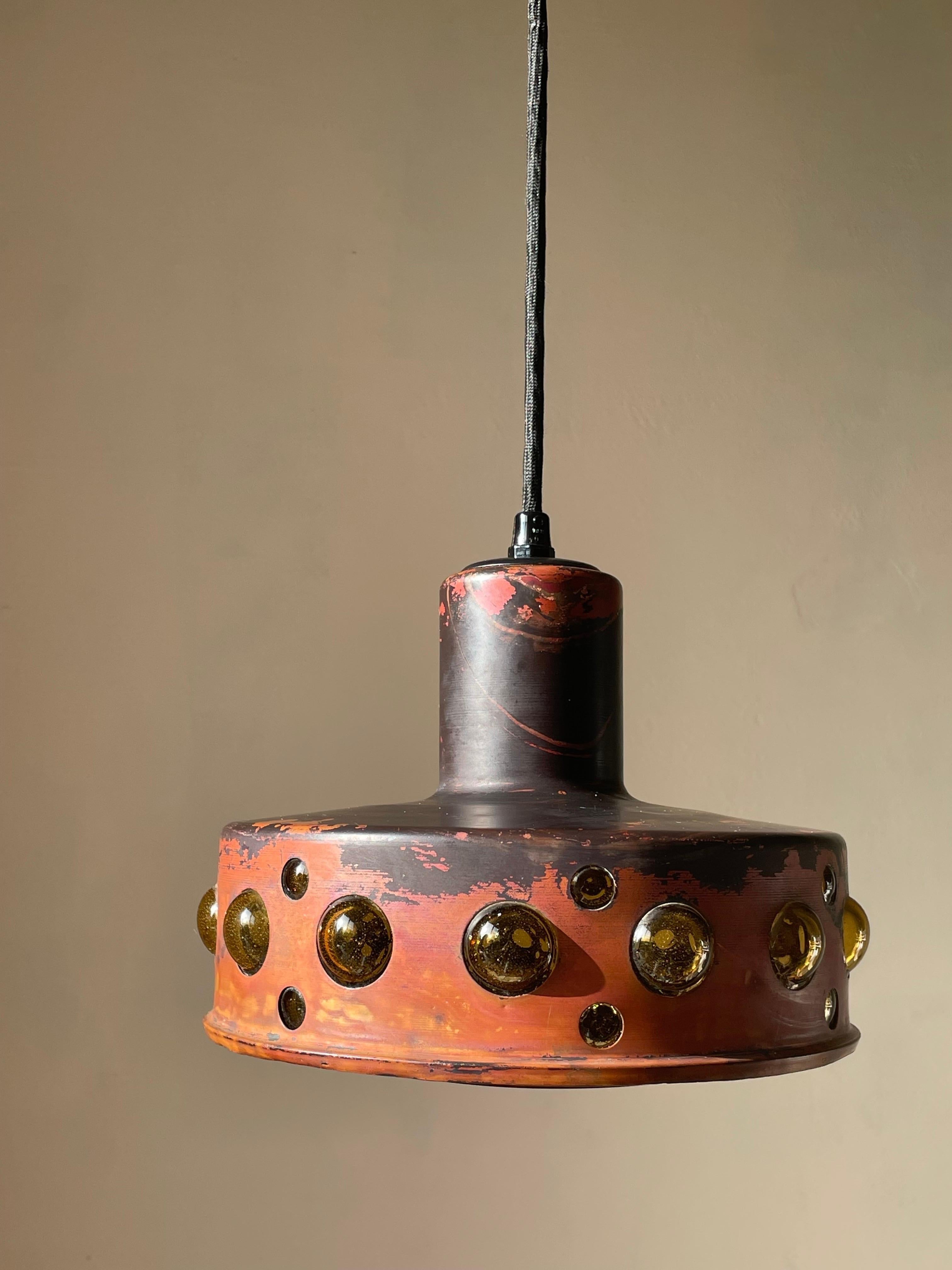 Rustic midcentury modern brutalist 1960s Finnish/Dutch ceiling patinated copper pendant. Thick textured amber glass cone covered with blackened copper that gives way to fourteen large and fourteen small 