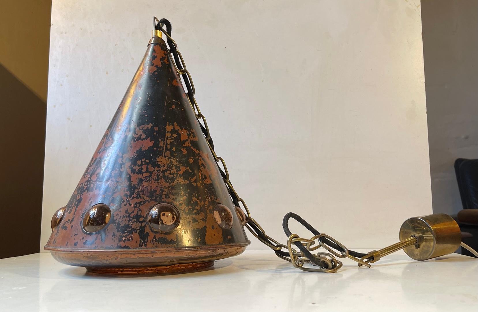 Acid-treated copper hanging light with an interior blown amber glass shade with penetrating bubbles. It was designed by female Finnish designer Nanny Still in the 1960s and manufactured by Raak Amsterdam. It comes chain-suspended and with its