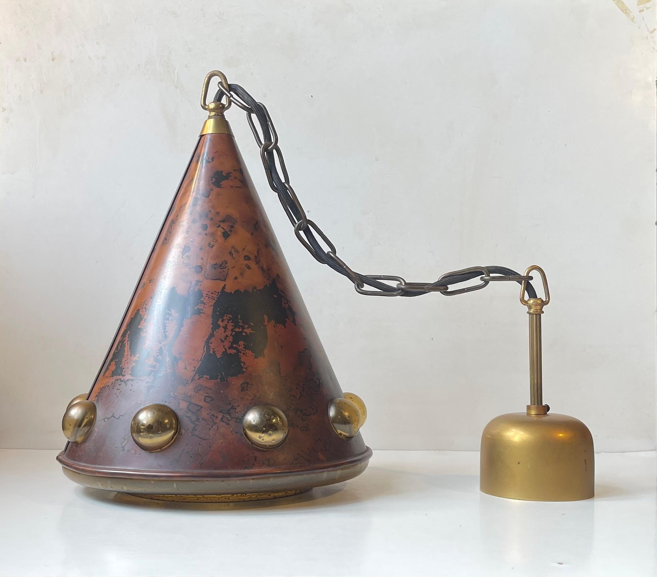 Acid-treated copper hanging light with an interior blown amber glass shade with penetrating bubbles. It was designed by female Finnish designer Nanny Still in the 1960s and manufactured by Raak Amsterdam. It comes chain-suspended and with its