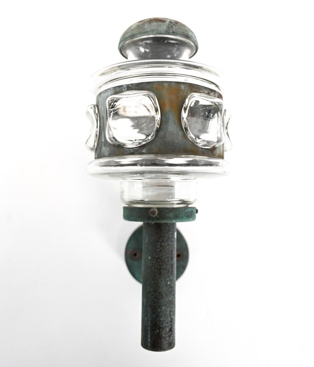 A Danish mid-century outdoor lantern form sconce in the manner of Nanny Still with interesting glass shade and patinated metal body.