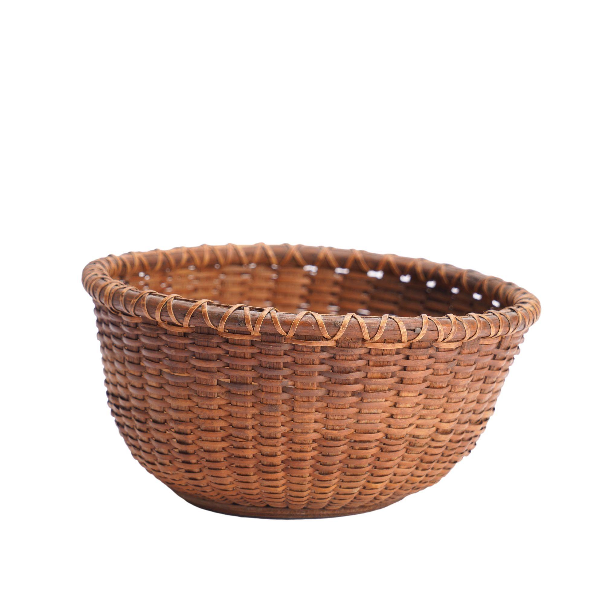 A classic vintage Nantucket berry basket with a turned hardwood base, scored with double incised circles. The base captures 41 curved ash stays woven together with split bamboo, and is captured by a split ash dowel at the rim, all of which is lashed