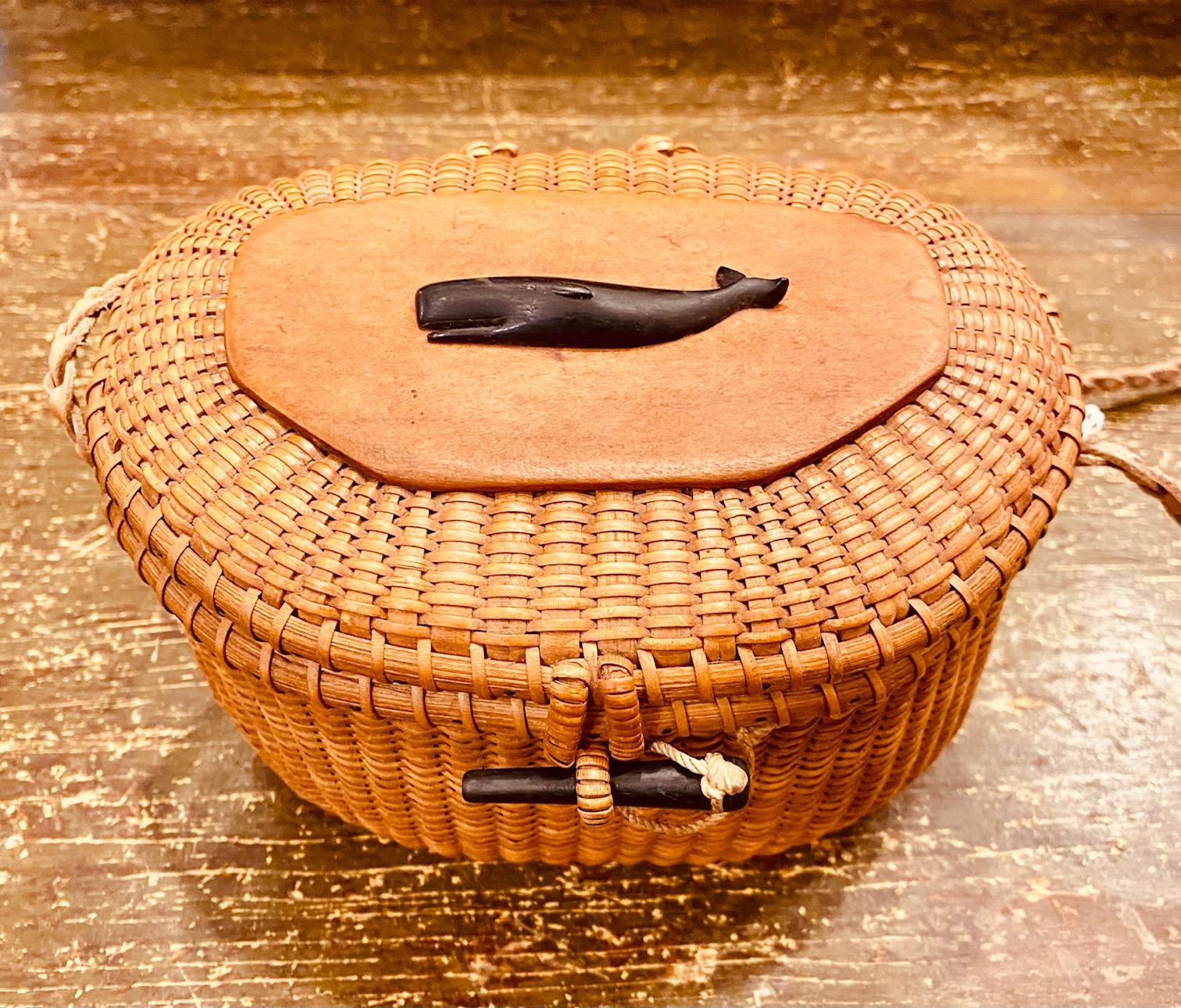 Vintage Jose Reyes Nantucket Cocktail Purse, circa Early 1950s, an early petite free-form creel-shaped covered basket with cane weave on cane staves, swing handle held by early copper rivets, and having a carved ebony sperm whale by Charlie Sayle