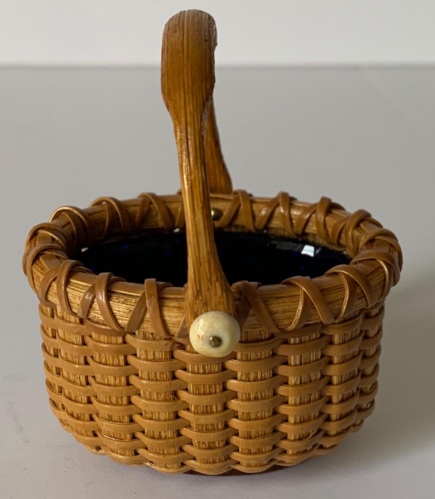 Nantucket basket salt cellar by Paul Willer. Miniature oval woven basket with attached handle. Cobalt glass liner. Signed 'Willer' on the underside.