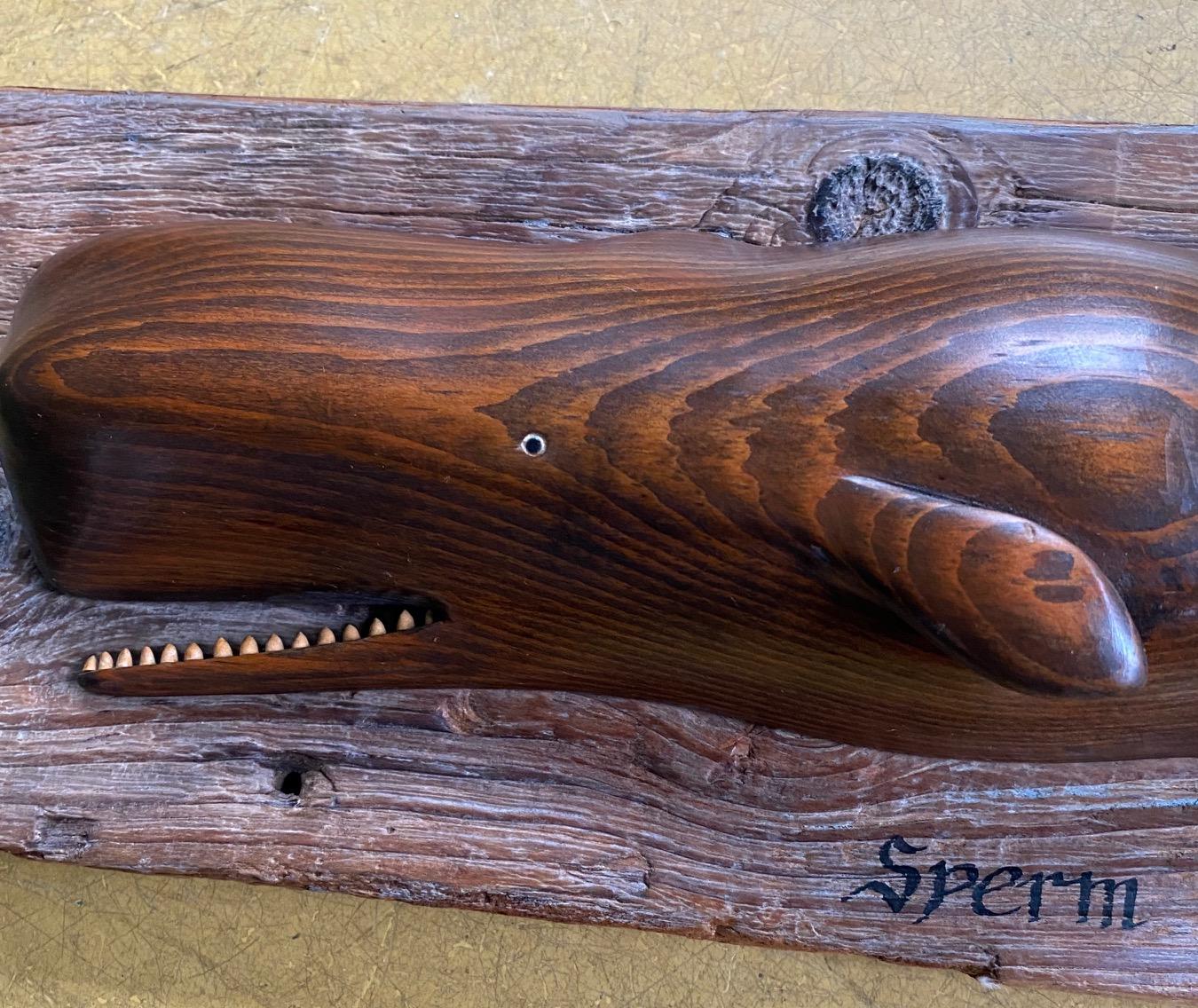 Vintage hand carved sperm whale by Nantucket artist William J. Dickson, 1971, a smoothly carved pine sperm whale with upraised flukes and open mouth exposing teeth, mounted on weathered barn board plank, signed and dated W.J. Dickson, 1971 on the
