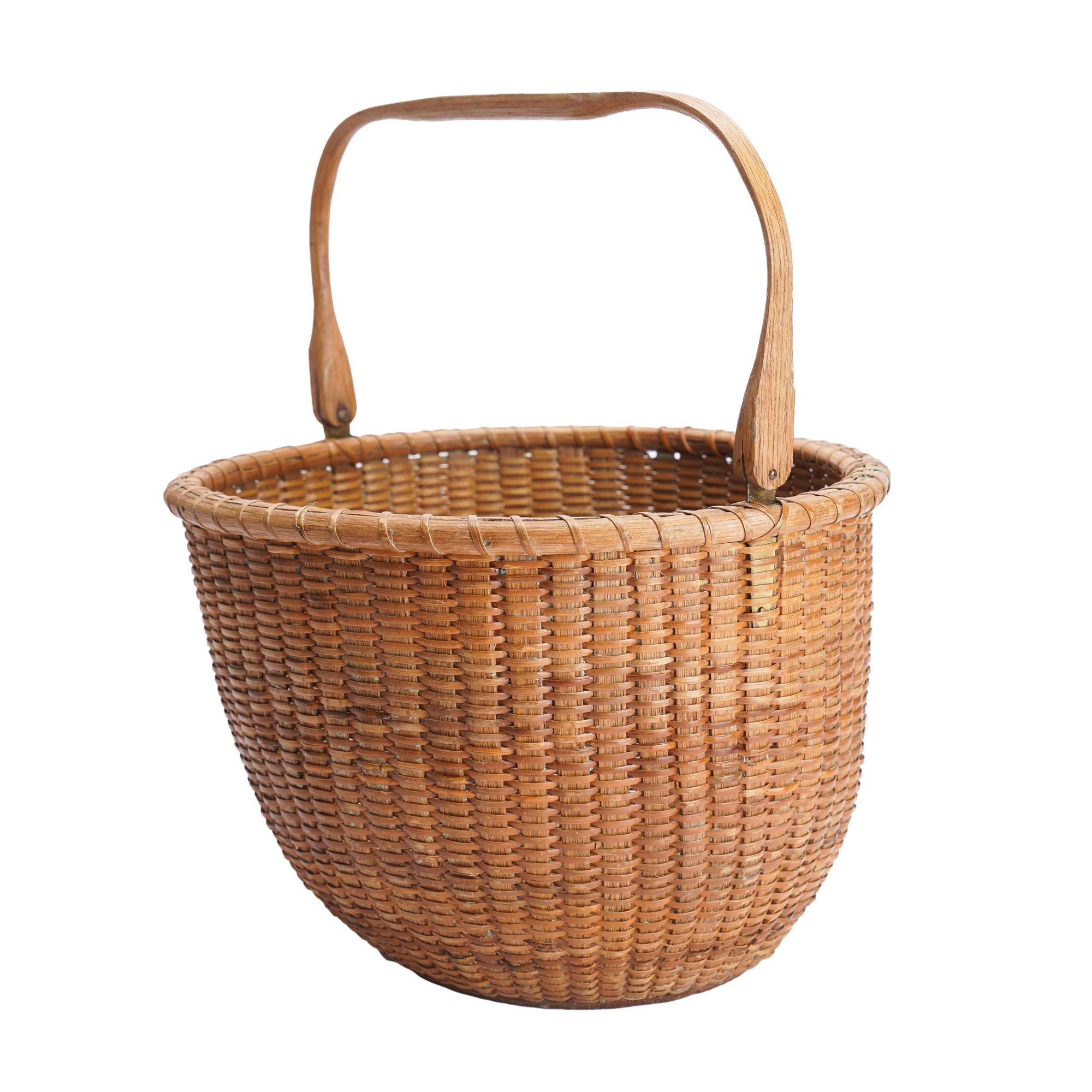 Large vintage Nantucket lighthouse basket with heavy rattan rim and stays. The basket features a hinged and carved oak handle which is squared off across the apex and carved with the initial 