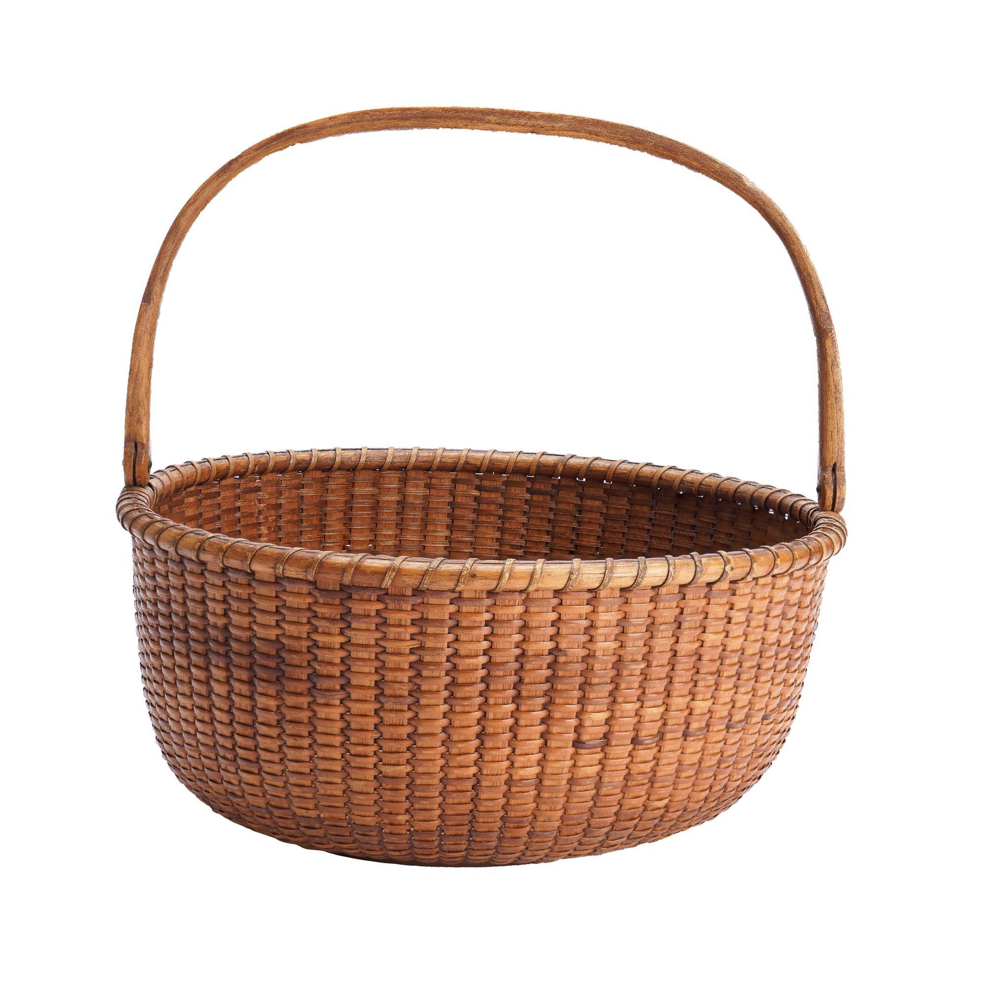 Round, open top Nantucket lighthouse basket in woven bamboo with oak stays, a slender carved oak handle with lollipop ends, and a round, hard wood bottom plate with two concentric scribed circles. The partial label on the under side of the basket