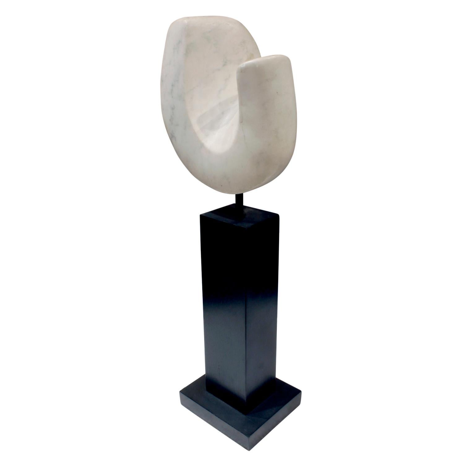 Hand-carved “Tenero” sculpture in Vermont marble mounted on an ebonized wooden pedestal base by Naomi Feinberg, American, 1960s.

Naomi Feinberg was a New York based sculptor who worked primarily in stone. She began sculpting in the 1940s and