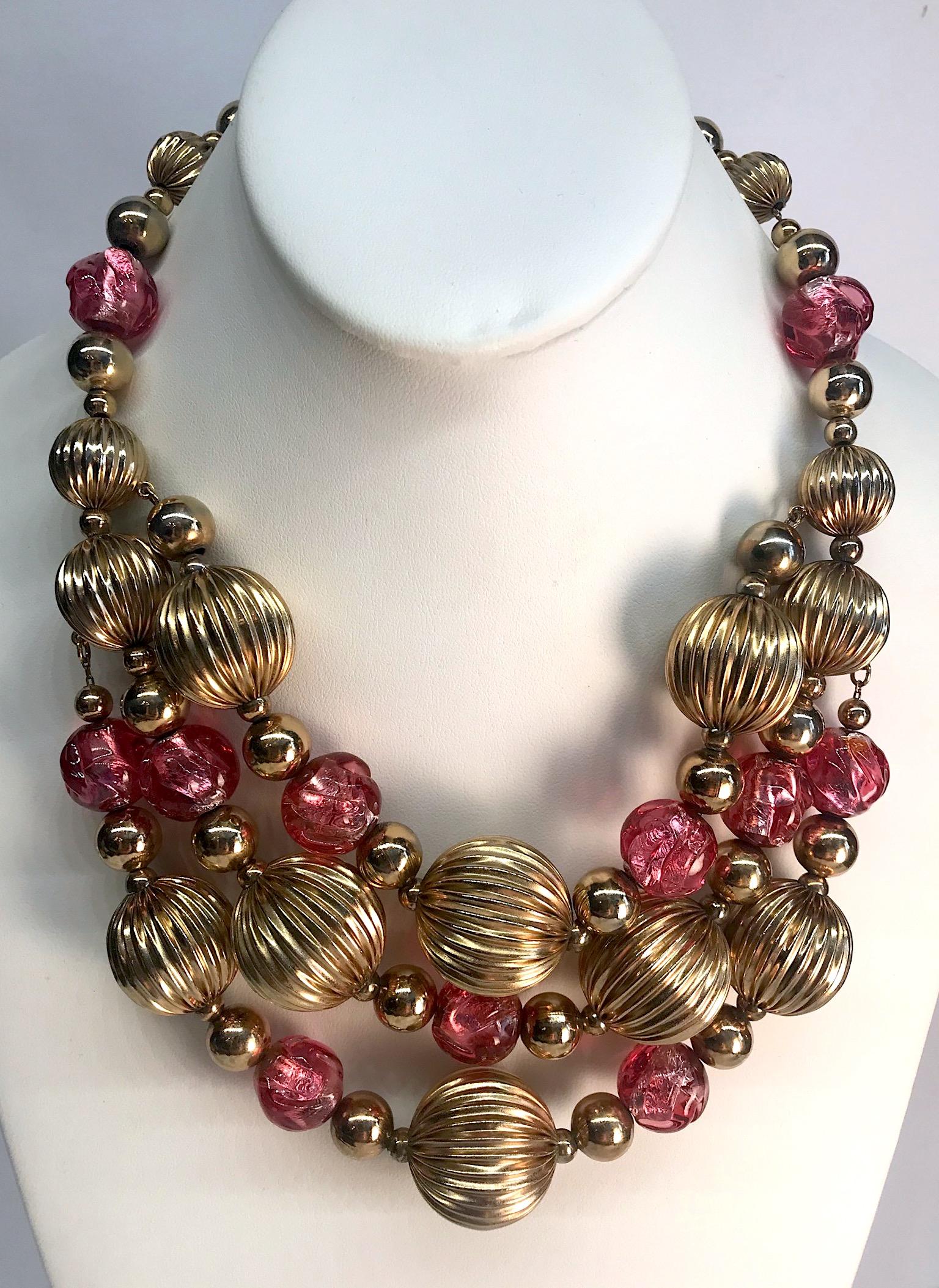 A lovey 1950s bib necklace from the American fashion jewelry company Napier. The front is bib style with three strands of gold plate and glass beads that meet a a single stand on each side. The largest gold ribbed beads are 25 mm (1 inch diameter)