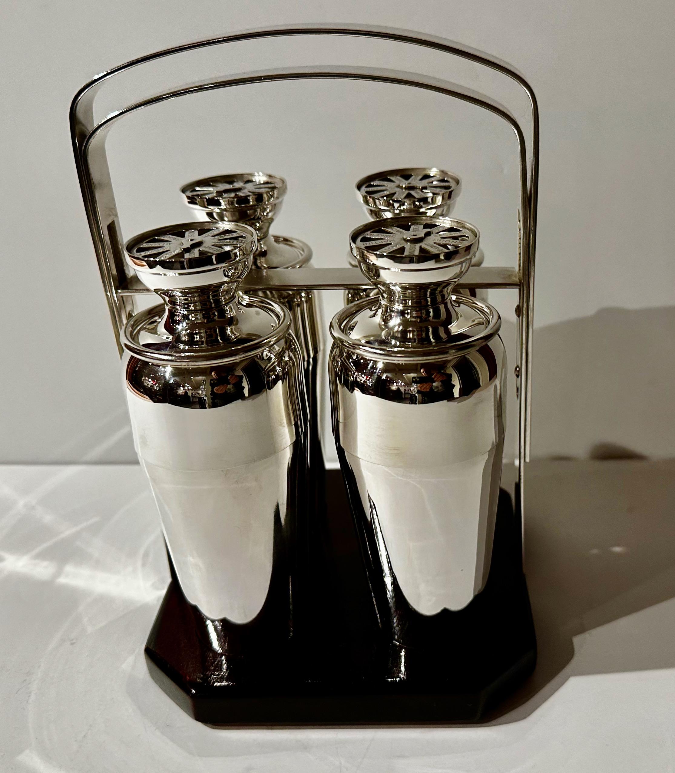 Set of four newly restored silver-plated cocktail shakers each with a cocktail selection dial on the top, contained within a Tantalus-like frame/Stand that secures the shakers in place when carrying. This wooden base caddy with a silver-plated