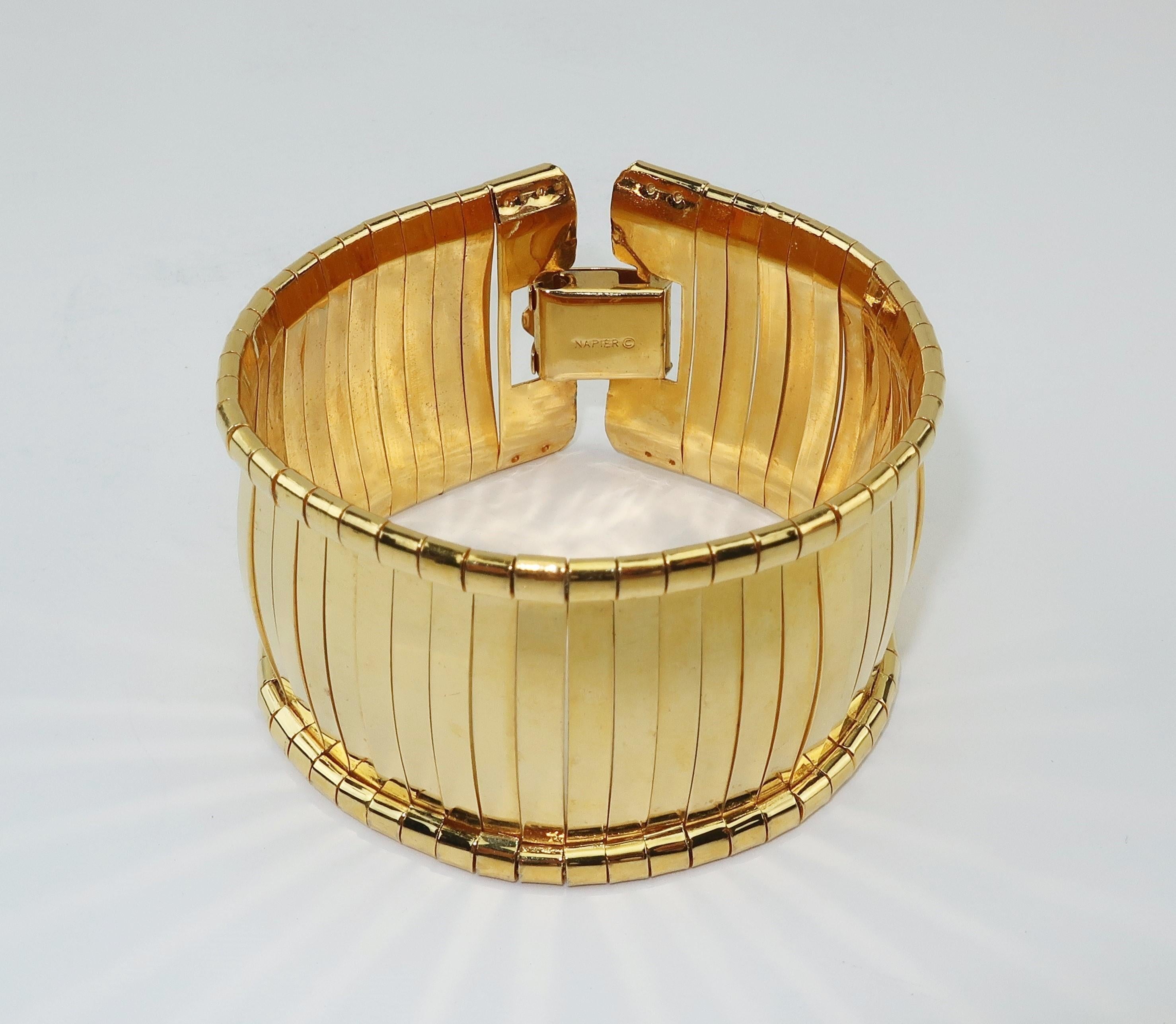 Napier creates a mod space age flexible bracelet with gold tone bands bowed to replicate a bangle silhouette.  The bands produce rays of light making it a real eye catcher.  It securely closes with a box clasp bearing the 'Napier' hallmark. 