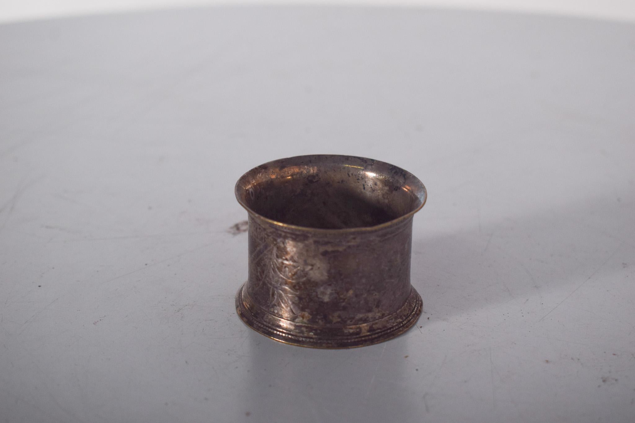 Portatovaglioli. In metallo argentato, presenta un bellissimo design classico con un tocco di eleganza antica. La forma cilindrica leggermente curva conferisce un fascino particolare al pezzo, che si distingue per la lavorazione artigianale della
