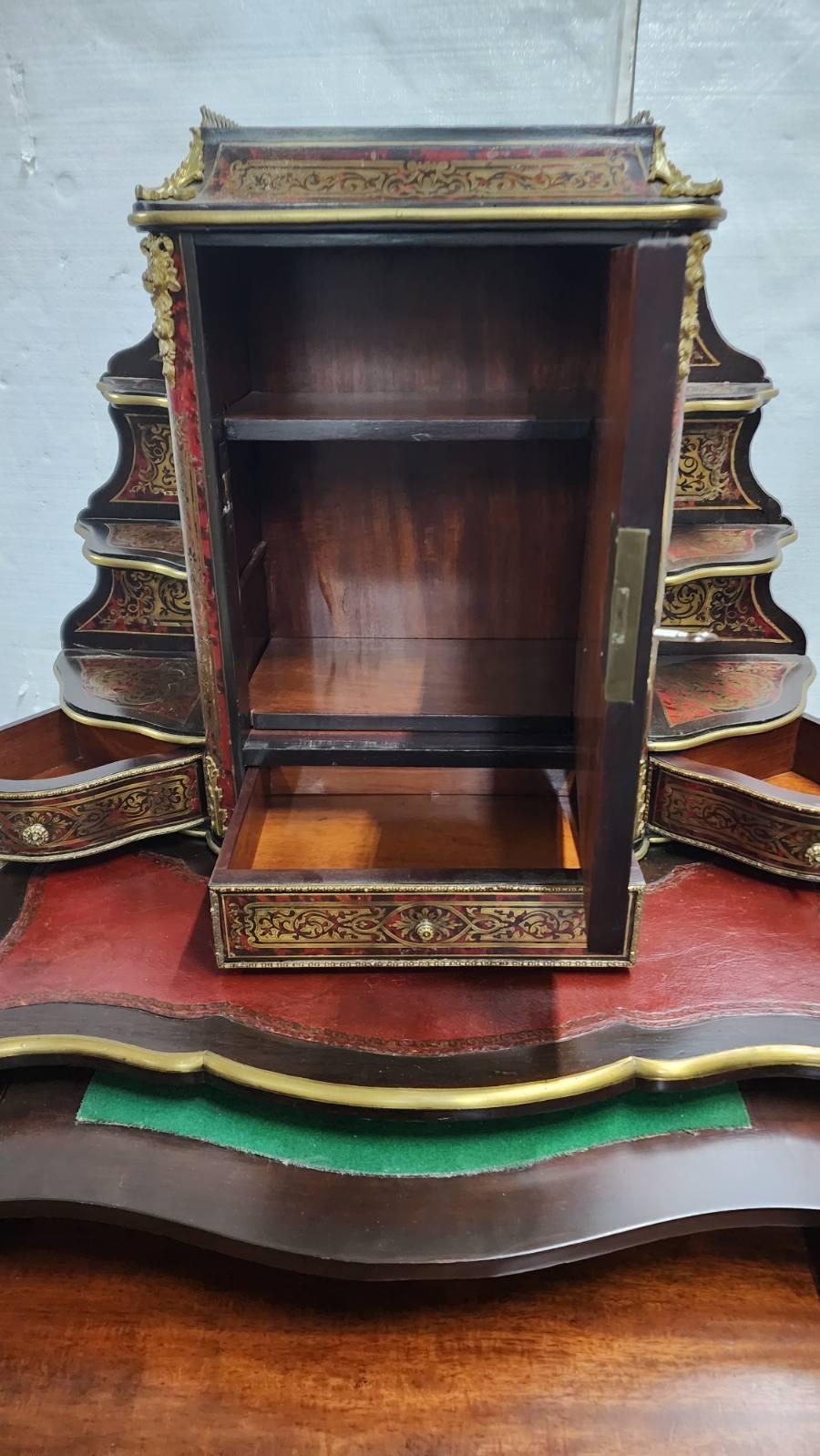 Damenschreibtisch aus dem 19. Jahrhundert, französische Periode Napoleon III, mit Intarsien im Boulle-Stil. Mit einer mittigen Schranktür, umgeben von offenen Einlegeböden, drei Schubladen und einer lederbezogenen Schreibfläche. Mit einem