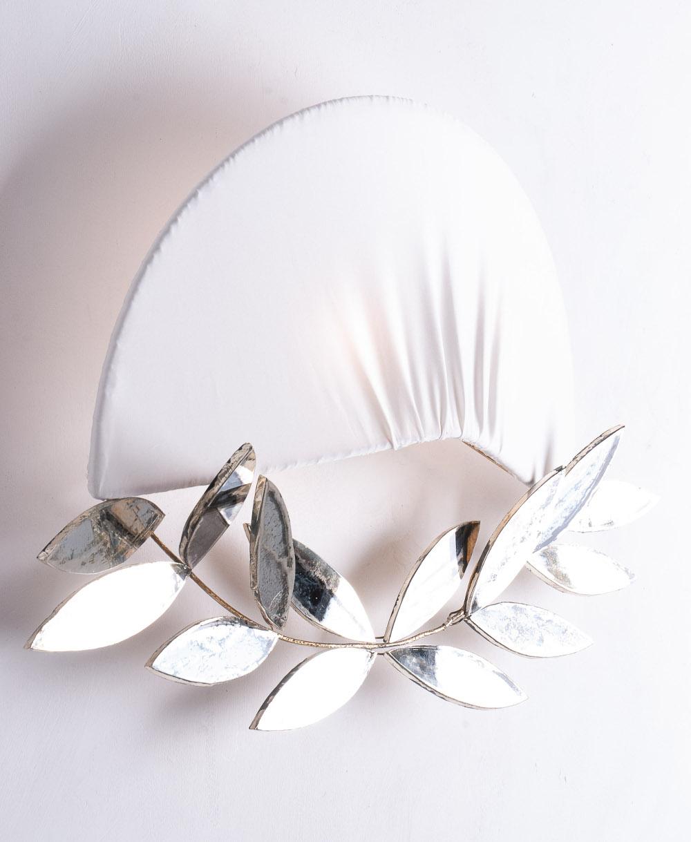 Inspired by the Academics ' high gala uniform, this unusual lamp seems to wear the Napoléon felucca-hat framed by an original laurel crown made of brass and glass leaves.
Silvered glass leaves are available in jade or smoky grey color, the silk