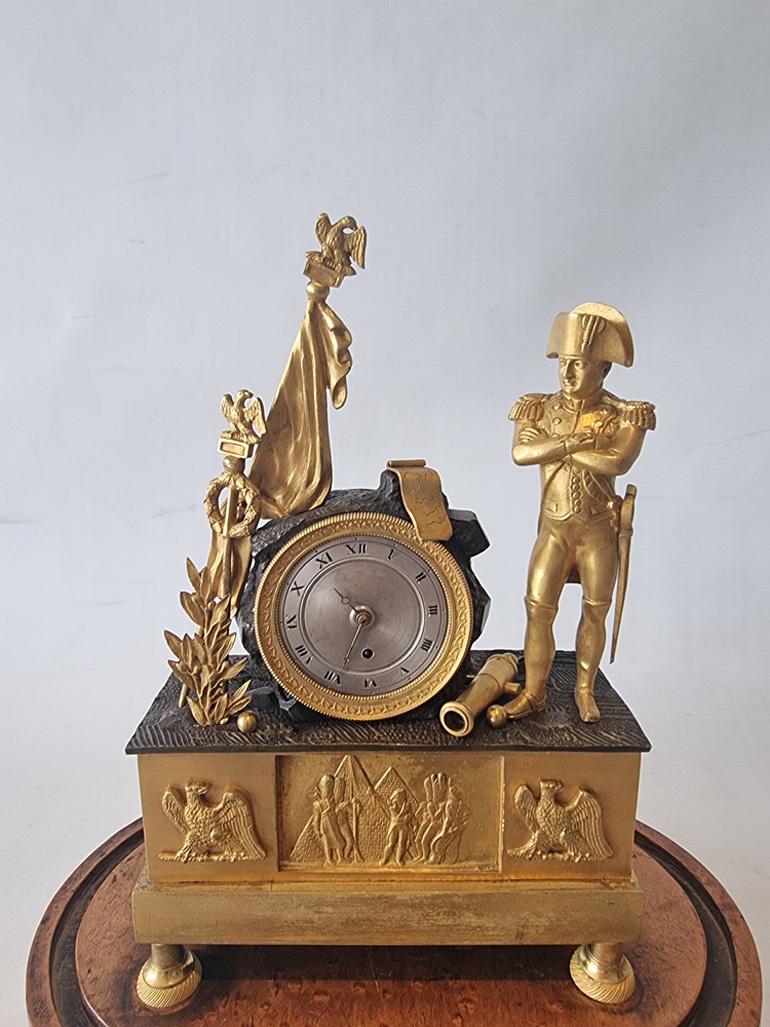 Eine seltene und ungewöhnliche französische Directoire/Empire-Uhr, die Napoleon inmitten von Kriegstrophäen wie Kanonen, Kanonenkugeln, Kartenrollen und Adlerstandarten darstellt. Das versilberte Zifferblatt mit eingravierten römischen Ziffern und