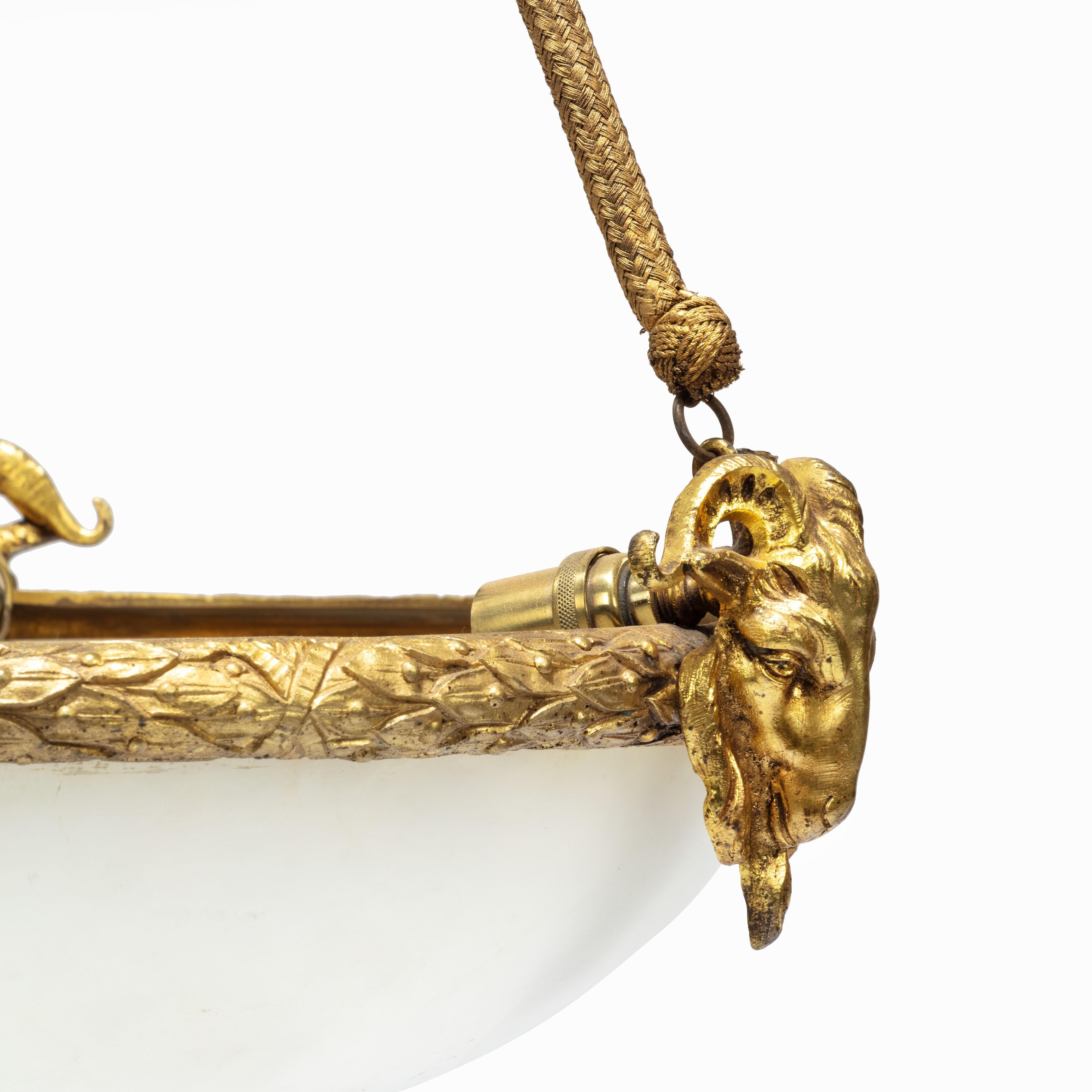 A Napoleon III alabaster hanging lamp, the alabaster bowl held within an ormolu wreath of laurel leaves and three rams head, suspended by three gilt-thread ropes from a tassel and leaf finial, French, circa 1870.
 
Measures: H 34”
W 18” diameter.