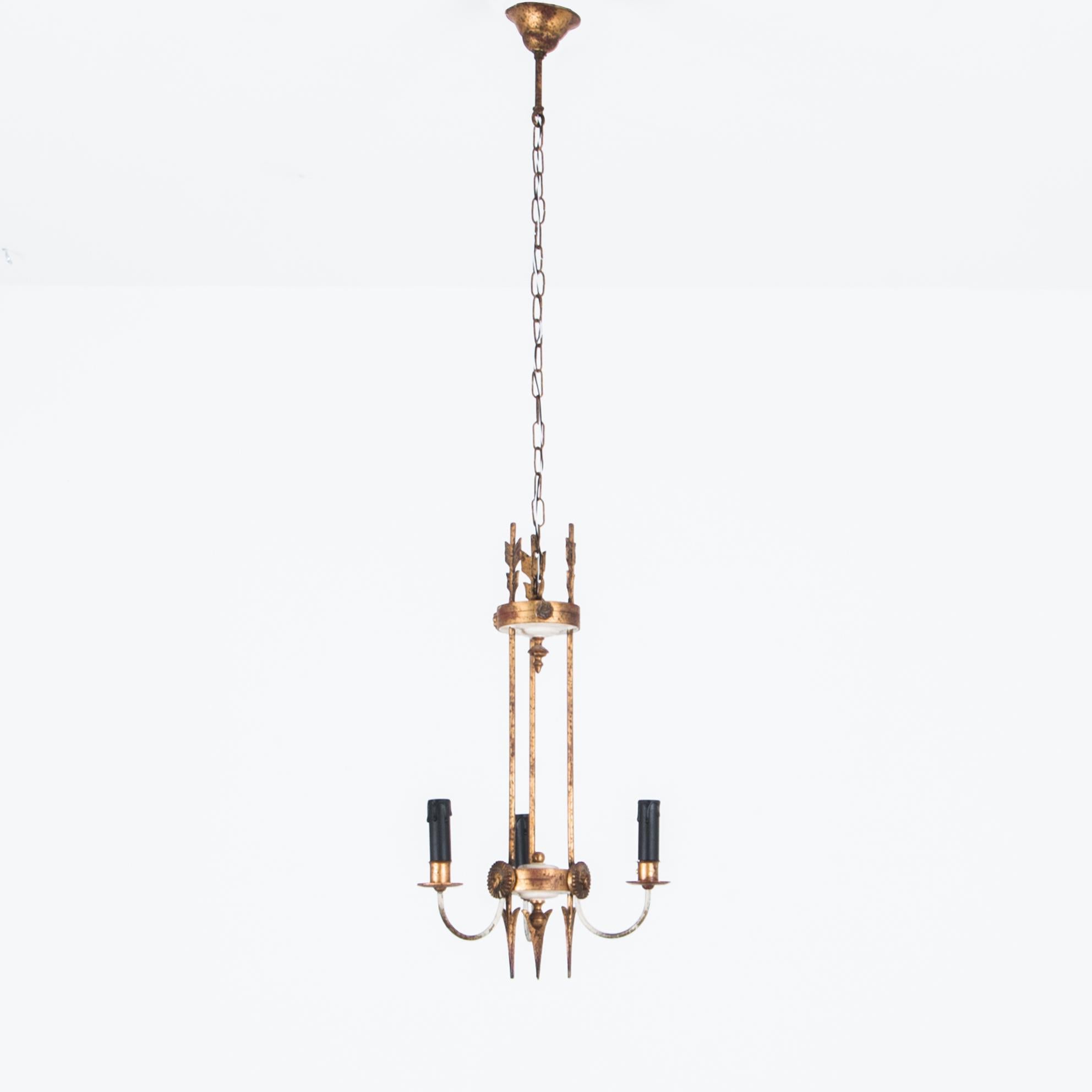 This gilded Second Empire style chandelier from turn of the century France provides a stately antique light source. A ceiling chain supports an arrangement of three golden arrows piercing radiant emblems; three curved arms emerge bearing atmospheric