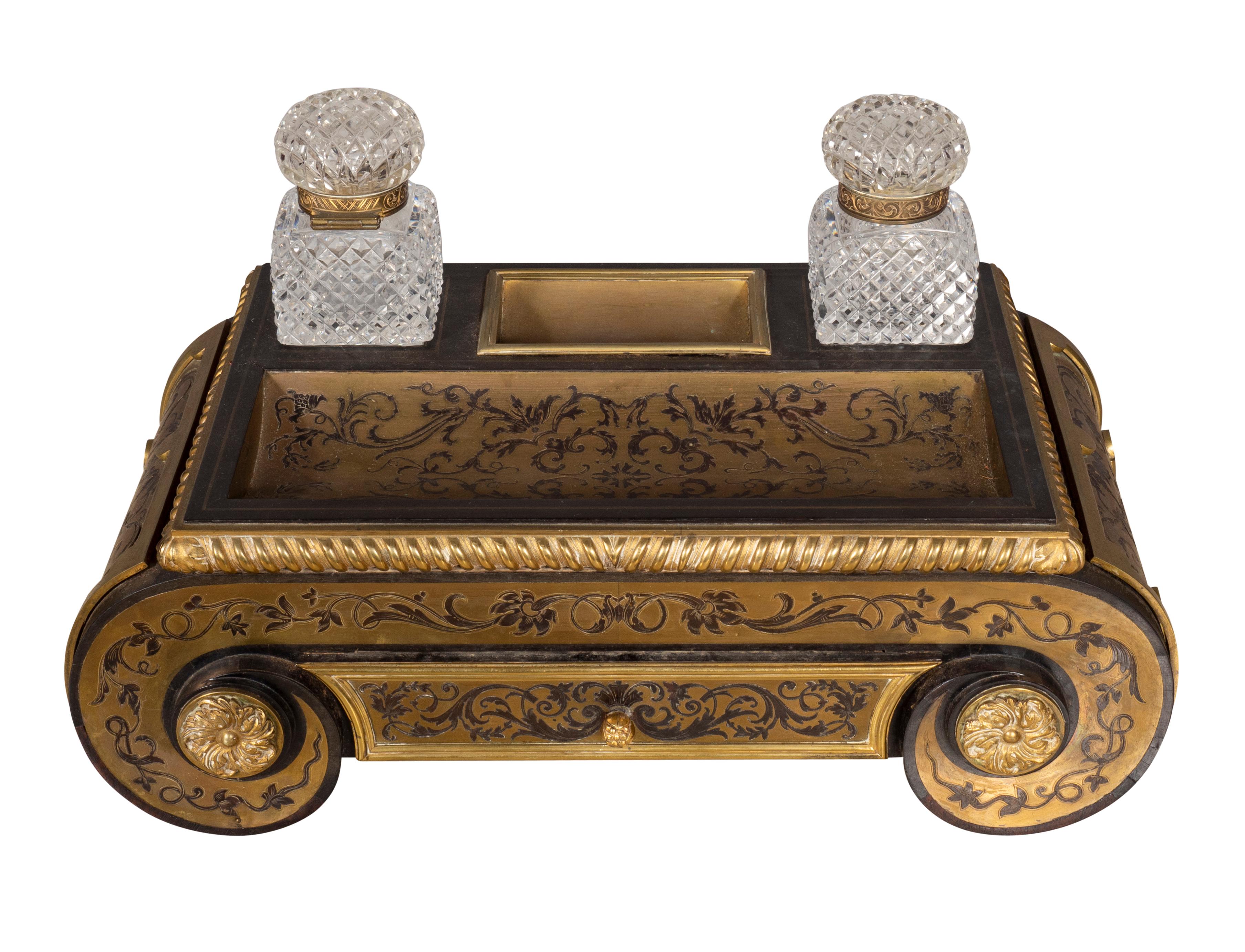 Rectangular with two cut glass inkwells and pen tray over a drawer. The sides rounded. The inspiration for the decoration from designs by the master cabinet maker Andre Charles Boulle from the court of Louis XIV.
