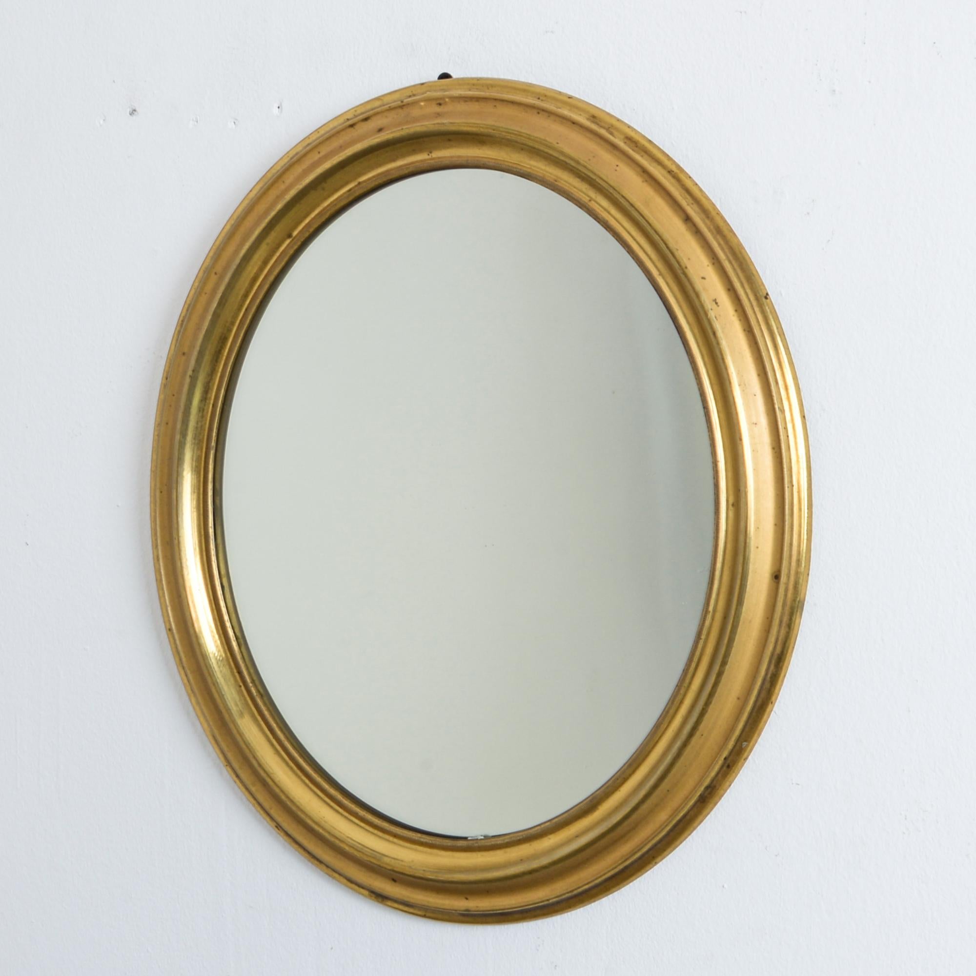 From France circa 1880. An oval brass mirror, in Napoleon III style. All original details, and a simple and dynamic form brings stylish French eclecticism and rustic European style to your space. These mirrors are made by beating a sheet or strip of