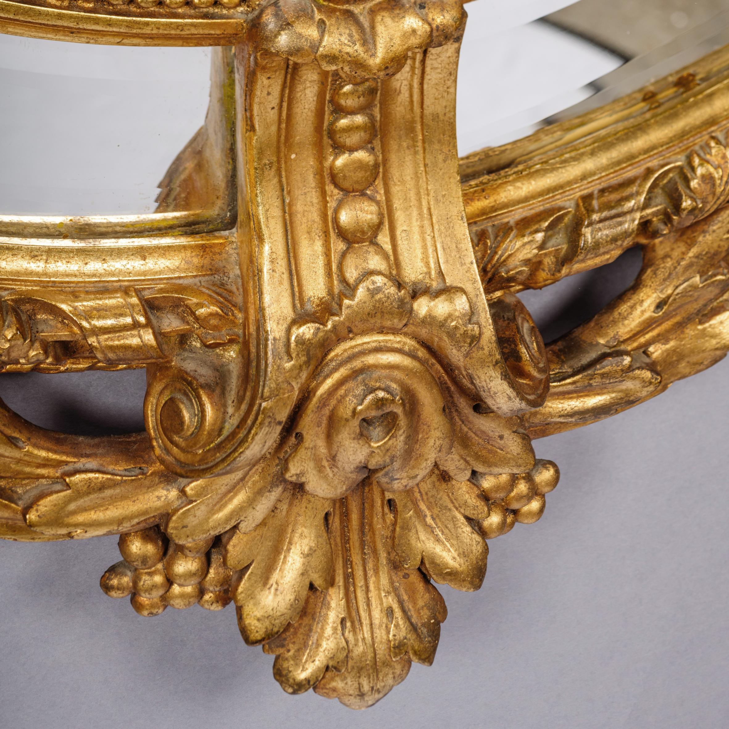 A fine Napoleon III Carved giltwood oval Marginal frame mirror.

This finely carved giltwood and gesso mirror has an oval bevelled mirror plate, marginal borders and an exuberant acanthus and foliate cresting centred by a basket issuing flowers.