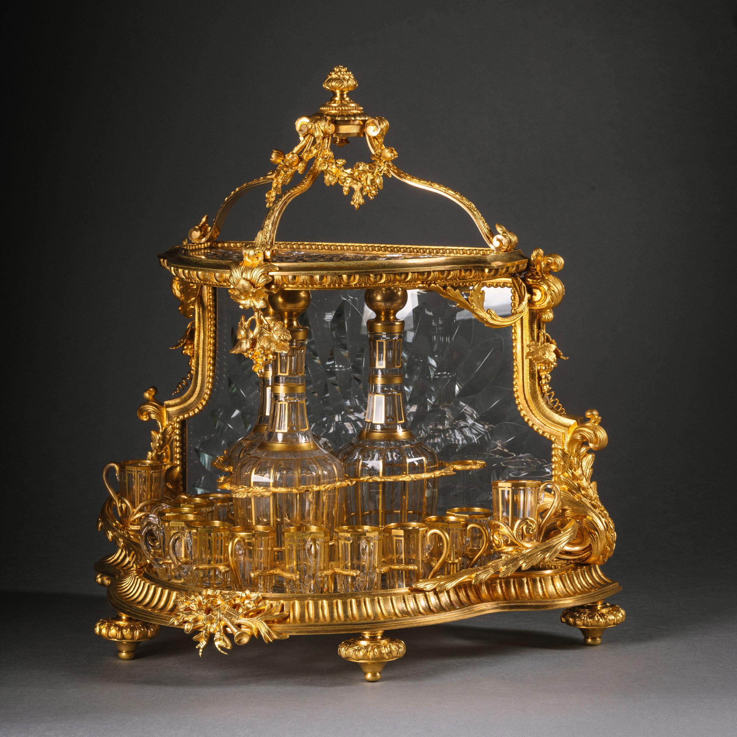 A Gilt-Bronze and Cut-Glass Pagoda Form Cave à Liqueur, Attributed to Baccarat. 

The shaped gilt bronze case finely cast with egg and dart moulding, acanthus fronds and musical trophies inset with radiating cut-glass panels opening to an interior