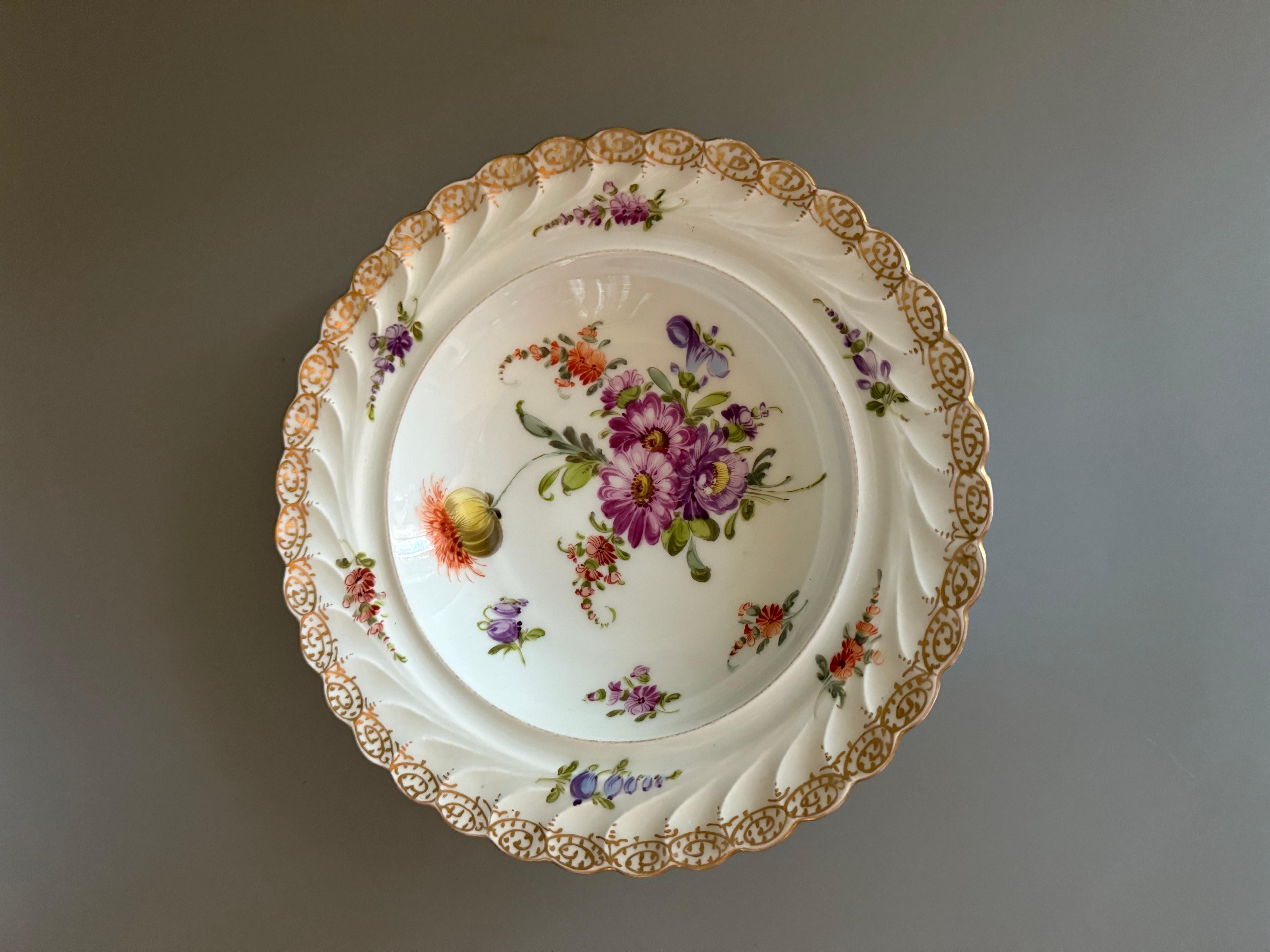   Antiker Dresdner Porzellanteller vom Ende des 19. Jahrhunderts mit handgemalten floralen Motiven und goldverziertem, gebördeltem Rand. 
Herkunft: Dresden,Donath & Co, Deutschland, bekannt für sein feines Porzellan. 
1872 in Dresden als Donath &