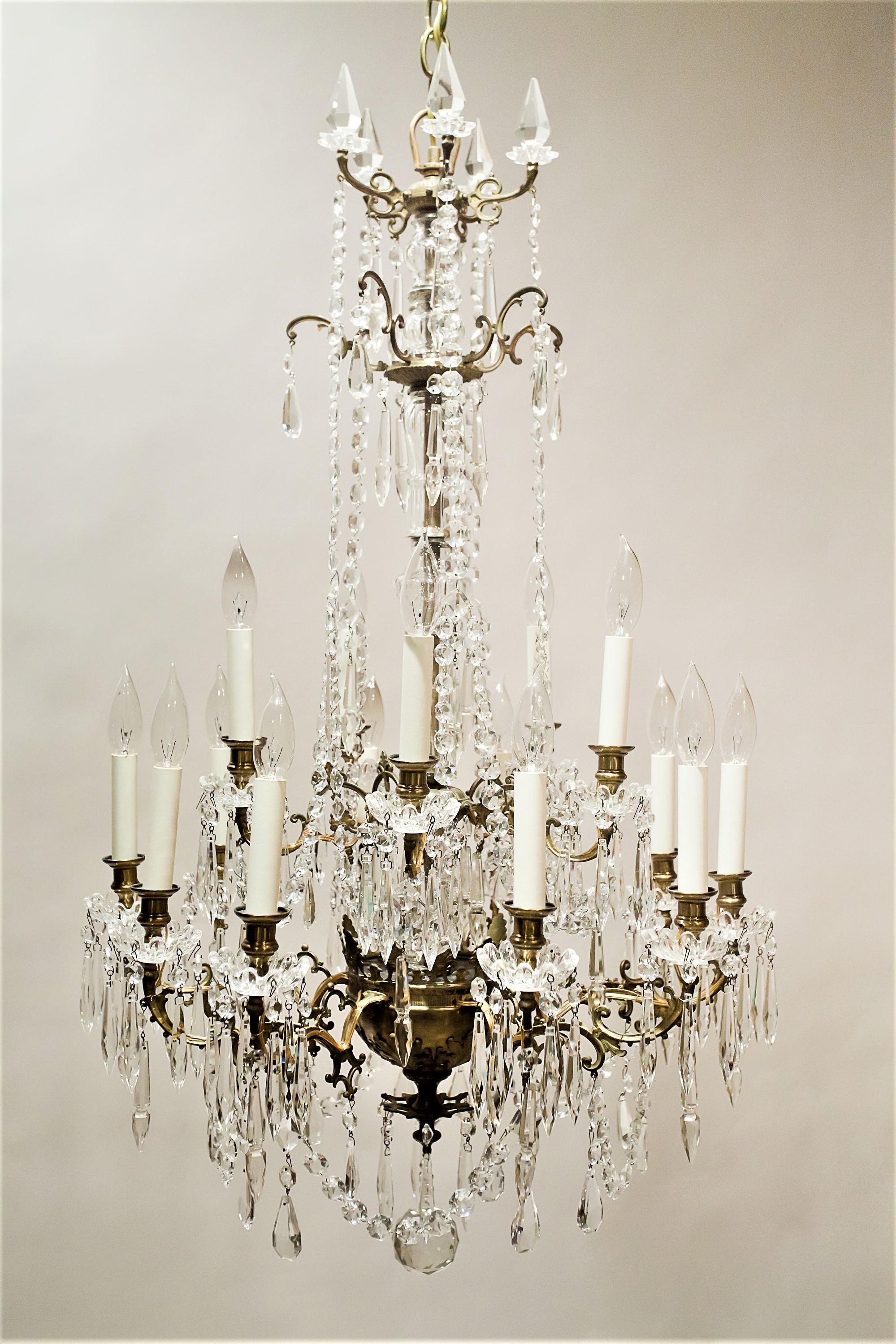 This imposing 15-light chandelier has lights in 2 tiers. The fixture is made of hand-cast gold-washed brass with handcrafted lead crystal prisms. The castings have a slightly Gothic design and the spear point prisms at the top are very unusual. The