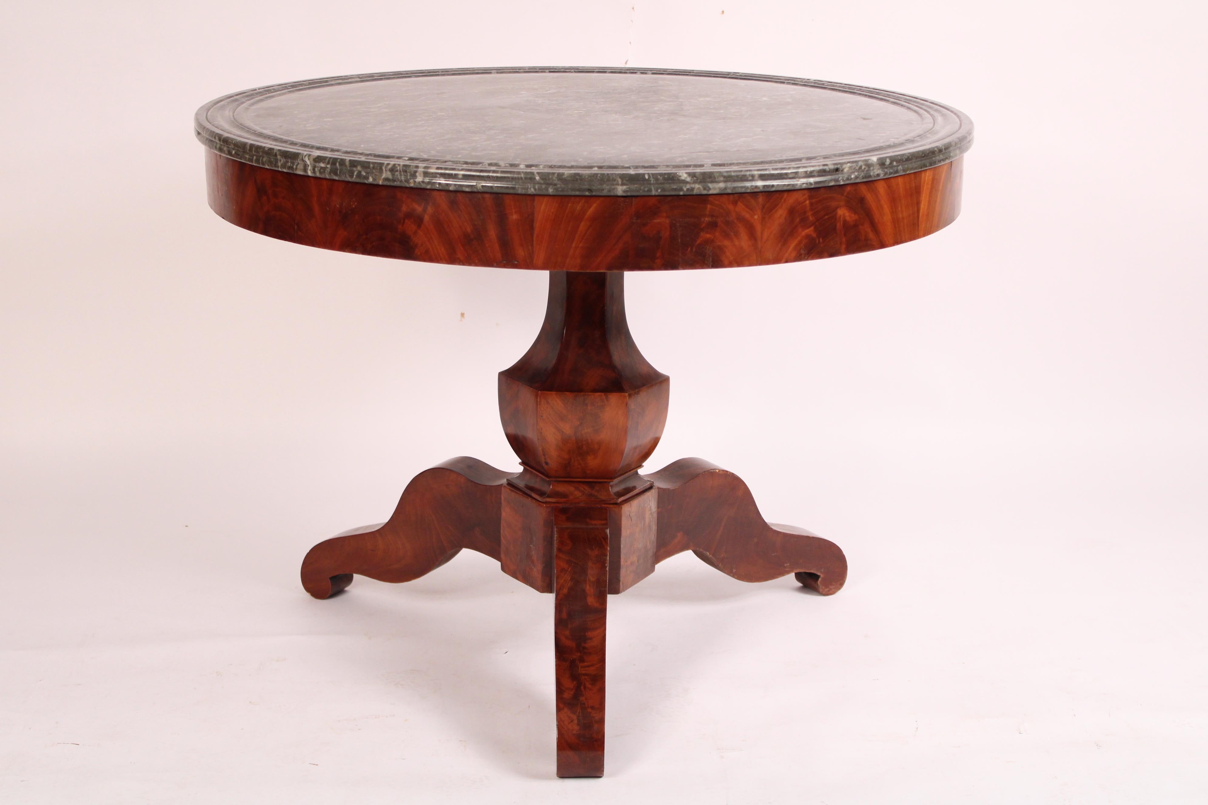 Napoleon III flame mahogany center table with marble top, circa 1850. With a gray and white Saint Anne's sandwich style marble top with grooved outer bands on the top, a flame mahogany apron, a flame mahogany vase shaped pedestal and 3 flame