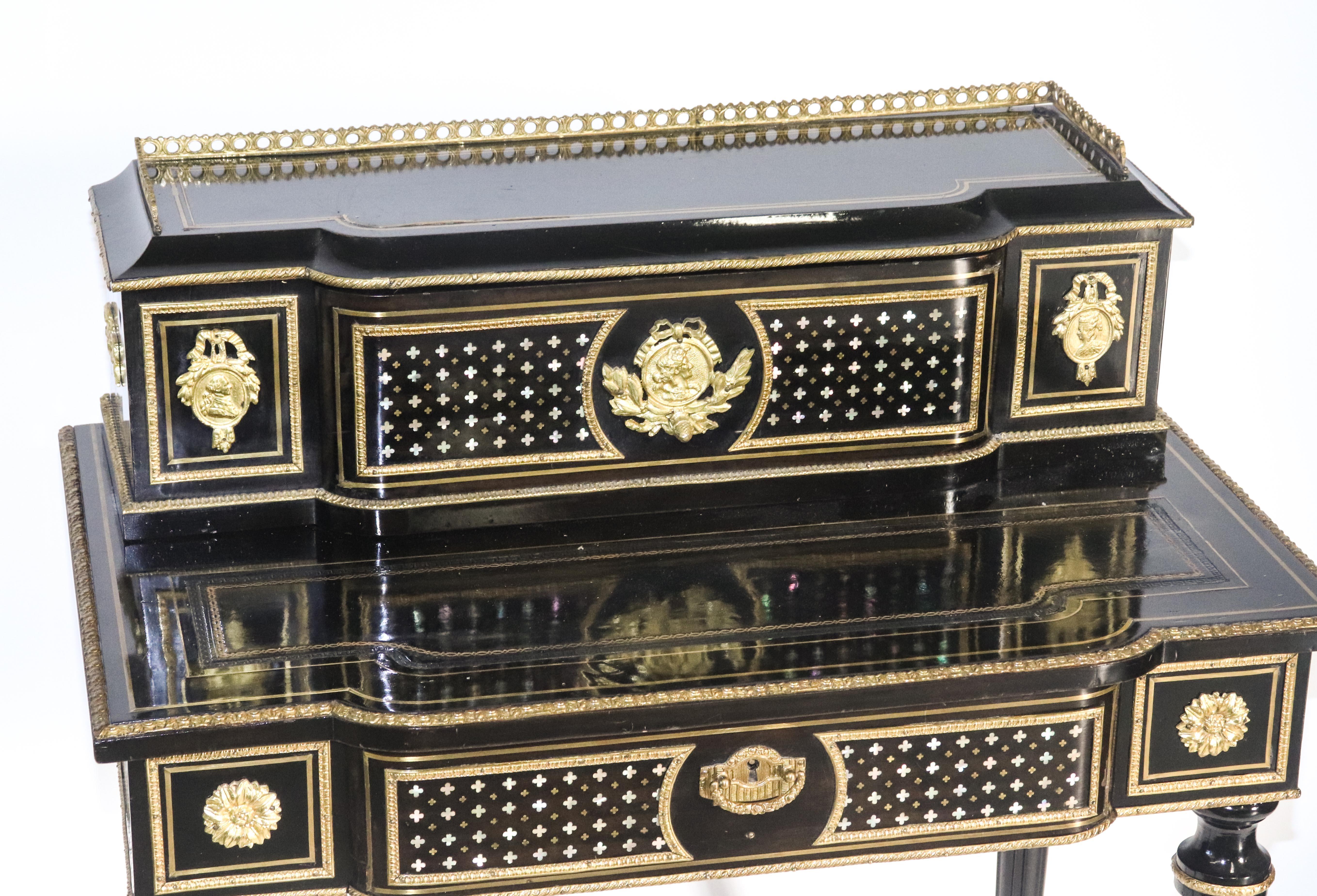 Napoleon III black lacquered Bonheur du jour diminutive writing desk, 20th century, throughout with brass inlay and gilt metal appliques, the desk with tooled leather writing pad, all over four turned and fluted legs. Measures: 36.75