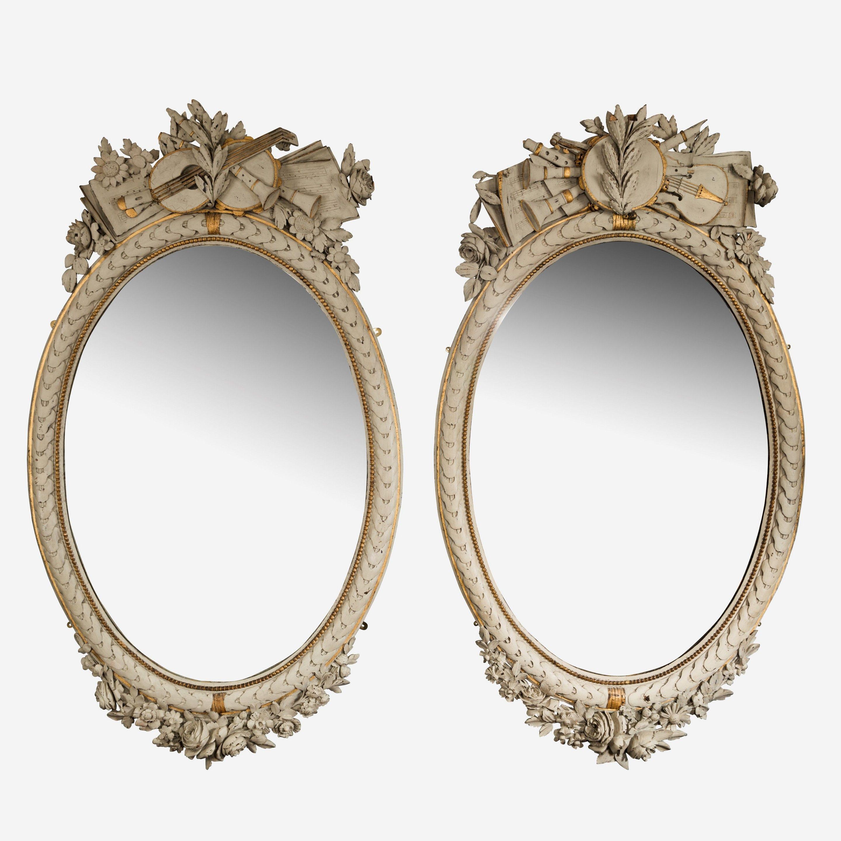A large pair of handed Napoleon III French oval mirrors. The cresting carved in wood and representing the arts with sheet music and instruments.
