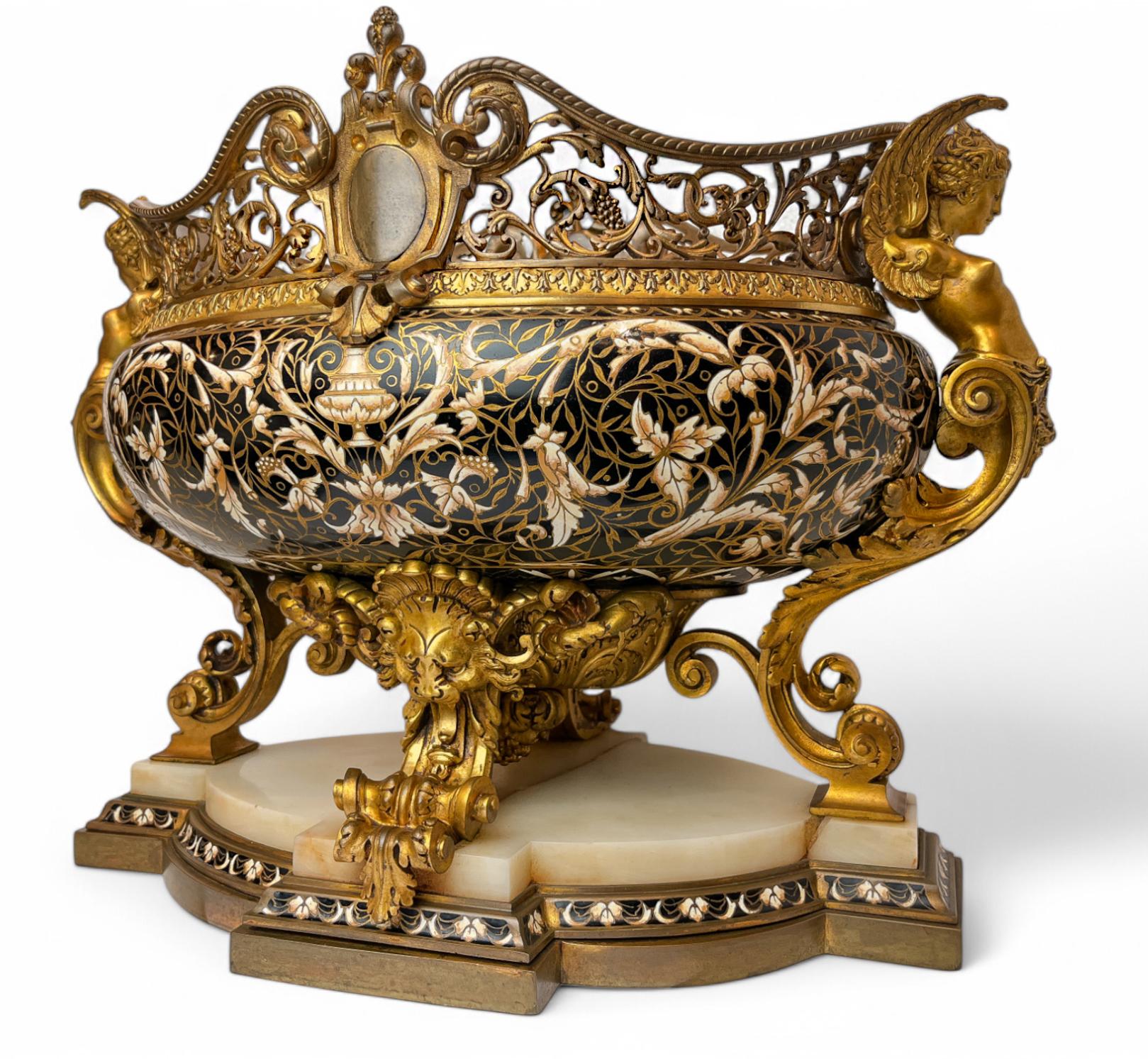 Jardinière Napoleone III in bronzo dorato e smalto cloisonné su base di onice bianco 

Questa jardinière di forma ovale è rivestita di smalto cloisonné nero, bianco e oro, con uno scudo sul bordo, sormontato da un fleur de lis e da volute foliate