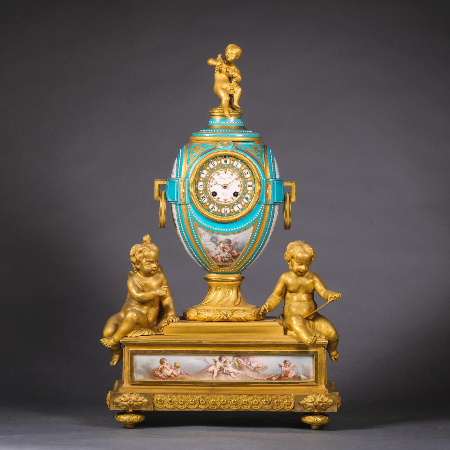 A fine Napoleon III gilt bronze and porcelain three piece clock garniture by Raingo Freres. The circular gilt and 'jewel' decorated porcelain dial of the clock with Roman numerals and signed 'Raingo Freres/Paris'. The ovoid case is painted with a