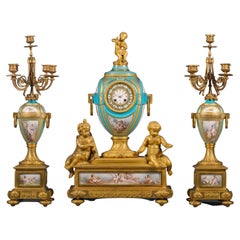 Napoleon III. Dreiteilige Uhrengarnitur aus vergoldeter Bronze und Porzellan