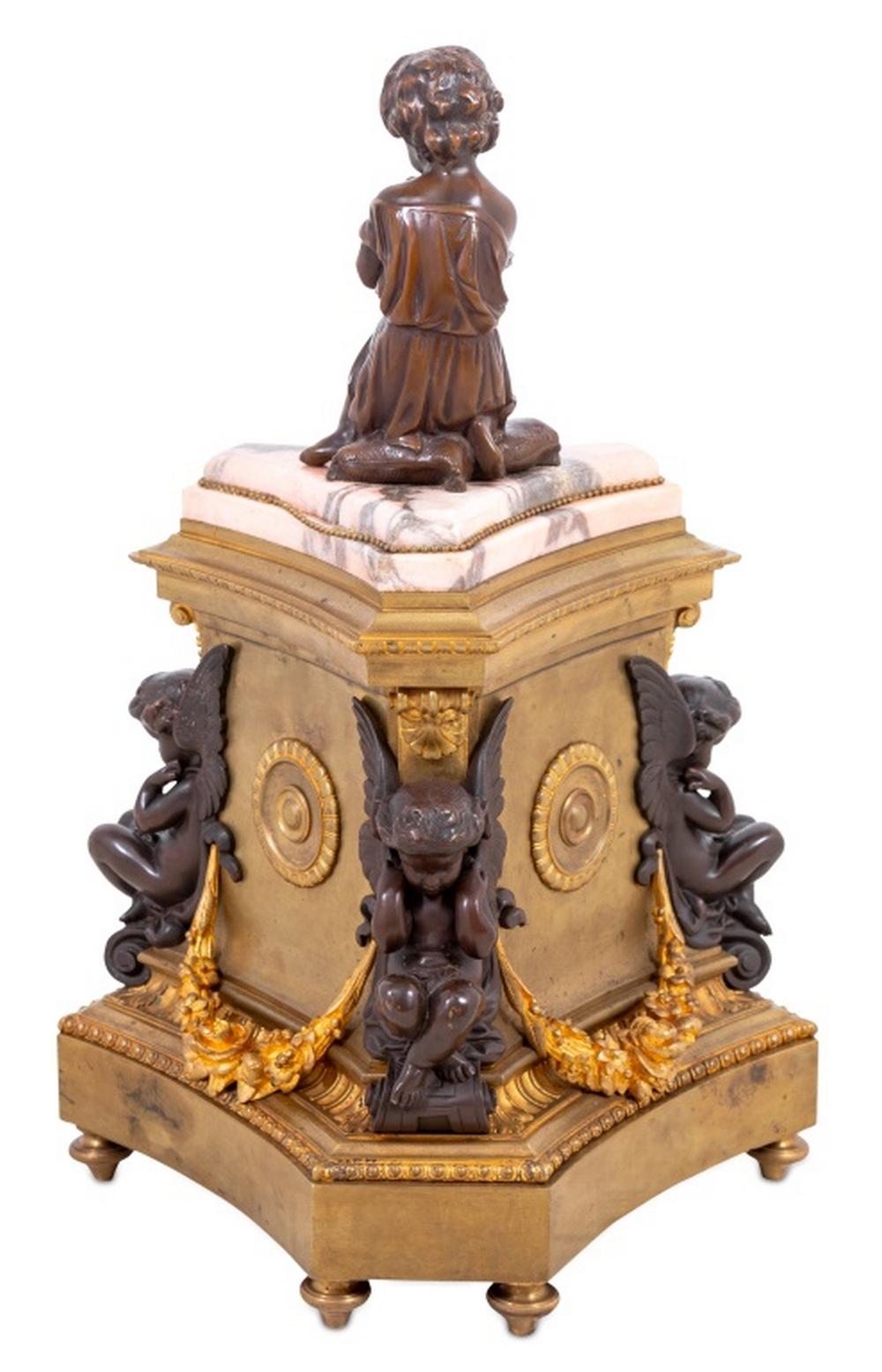 Napoleon III Gilt and Patinated Bronze Figural Clock, 19th century, of triangular form, the pink marble top surmounted by seated child, below the circular enameled dial with cherub supports, foliate scrolls, and concave plinth placed on toupie feet.
