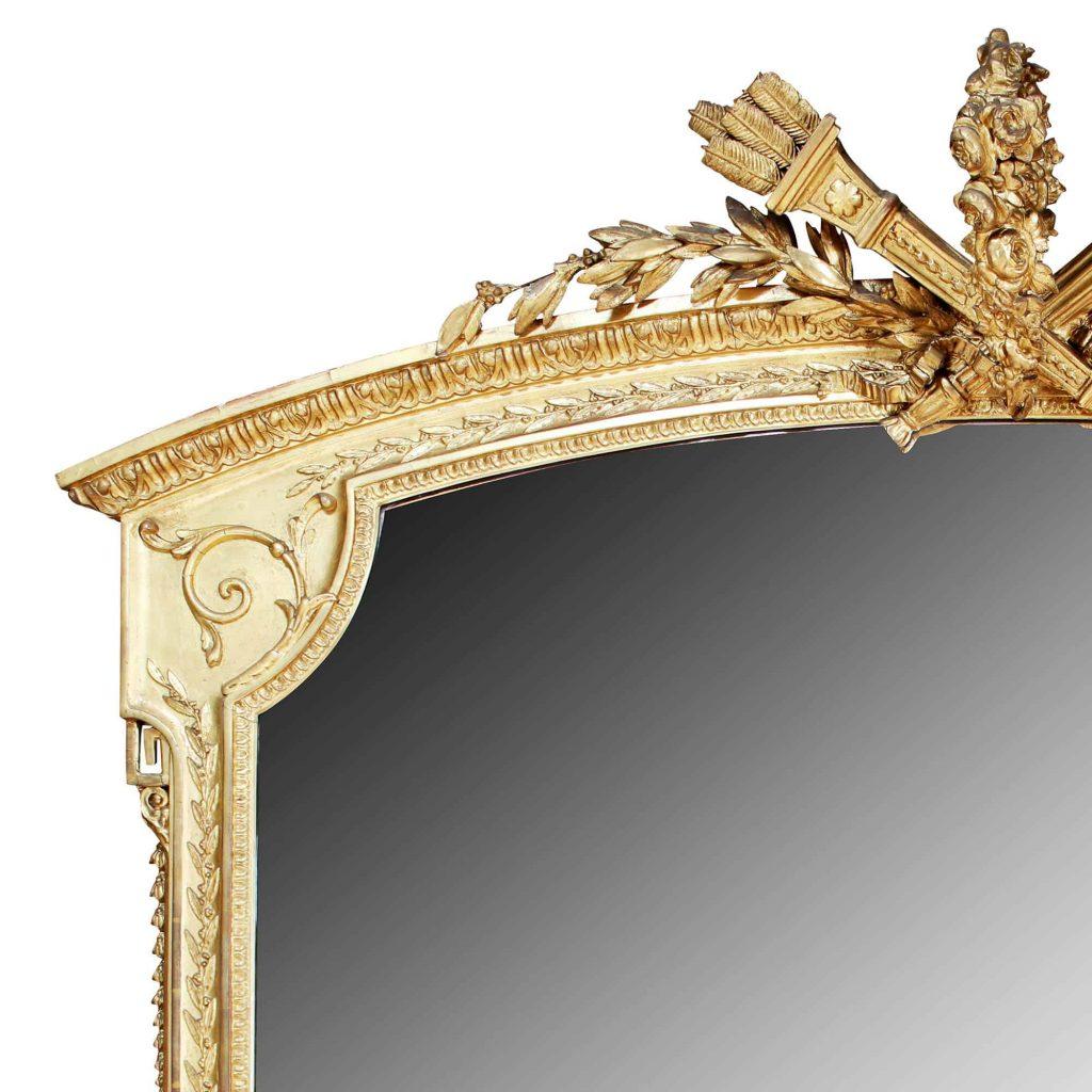 Palatial scale giltwood and composite overmantle mirror. The top with a quiver of arrows, a flaming torchere, garland of flowers and laurel leaves, the frame with carved detailing and foliate ornament.

England, circa 1880

Measures: Height