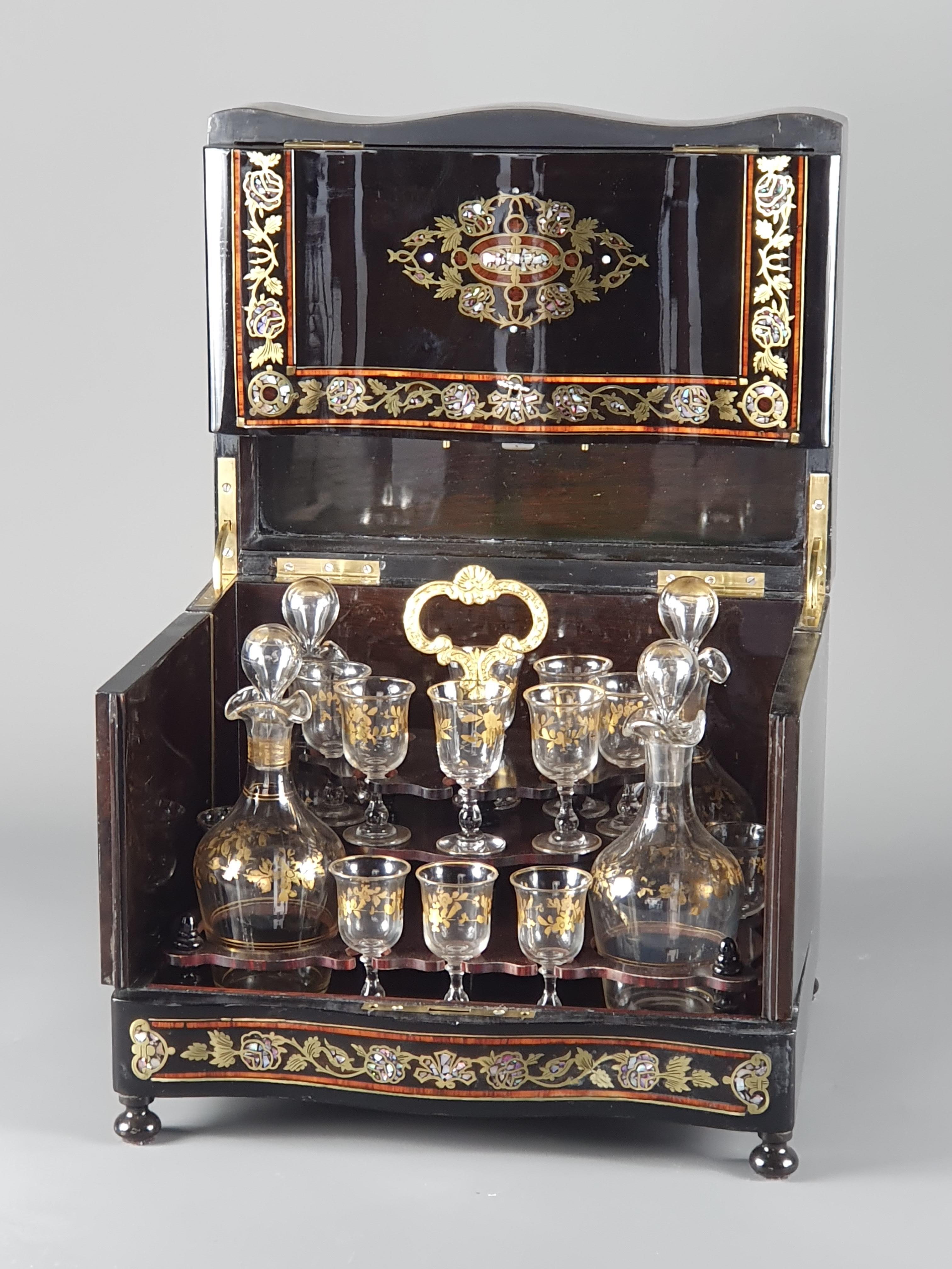 Beautiful Napoleon III liqueur cellar in blackened wood and marquetry of brass, mother-of-pearl, and rosewood fillets. Interior lined with a crystal service with beautiful floral decorations gilded with fine gold, consisting of 4 carafes and 15