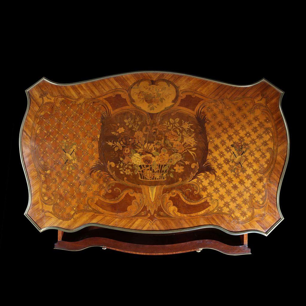 An elegant 19th century marquetry and ormolu bureau plat desk, the shaped top with central marquetry flowers, ormolu border above a single long drawer with fabric inspired mounts draped across the apron. The whole raised on cabriole legs with ormolu