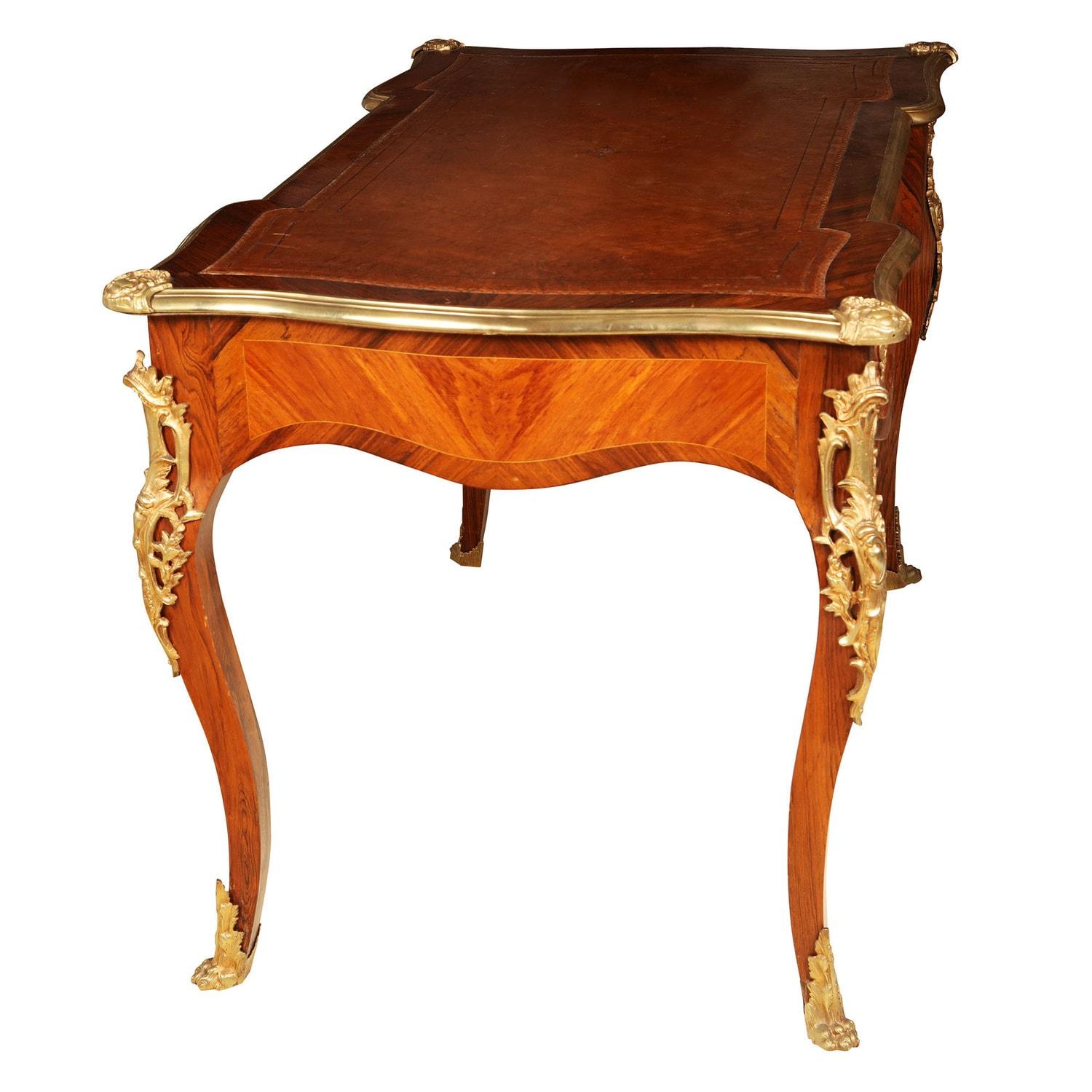 A late 19th century Napoleon III bureau plat desk in the Louis XV style, the shaped top with bronze molding above three drawers and supported on cabriole legs with foliate gilt mounts and hairy paw feet.
France, circa 1880
Measures: Height 78cm