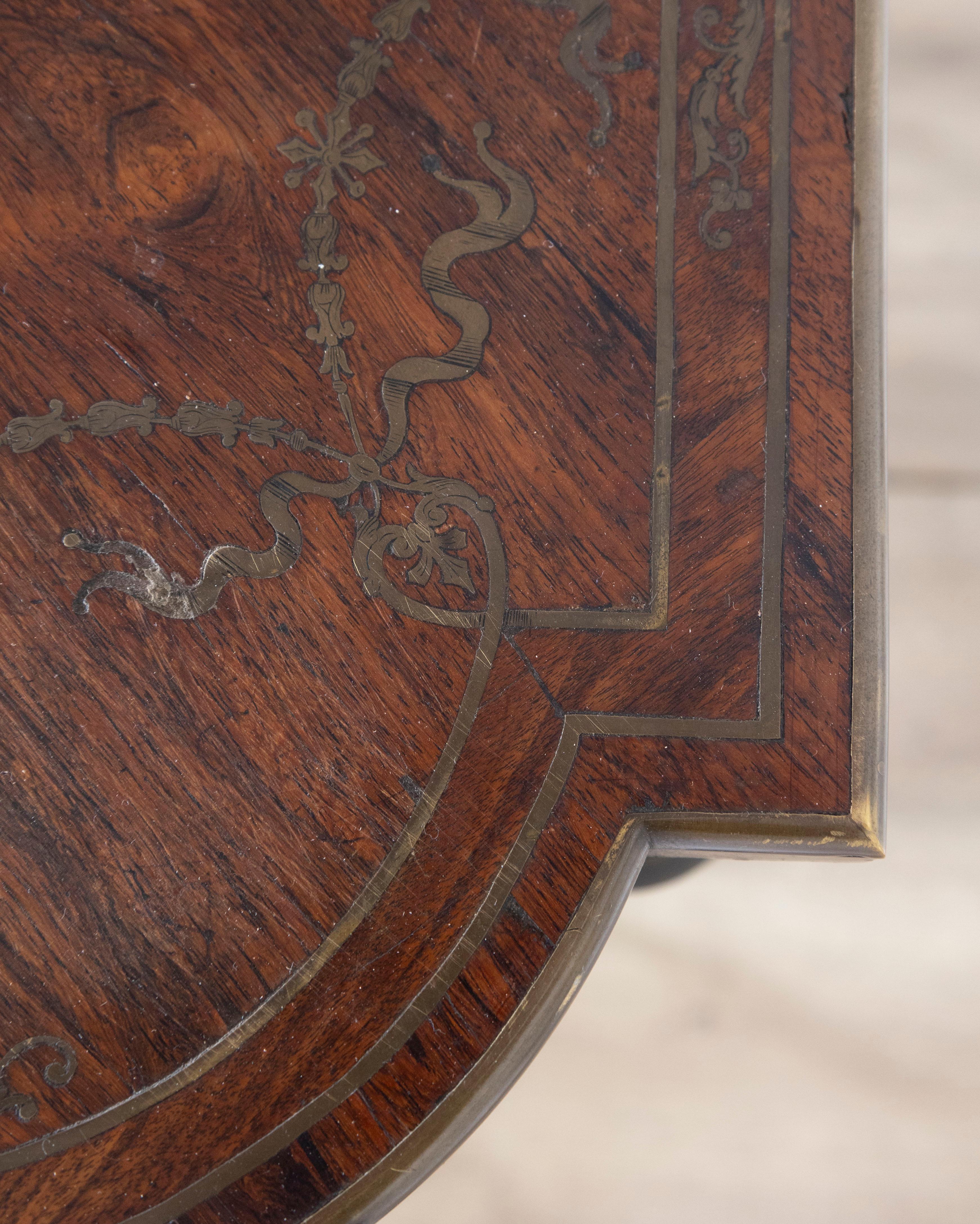 Cette table d'appoint raffinée Napoléon III, datant d'environ 1870, incarne l'élégance et le savoir-faire de la France du XIXe siècle. Le plateau de forme est magnifiquement incrusté de marqueterie, représentant un vase central de fleurs entouré
