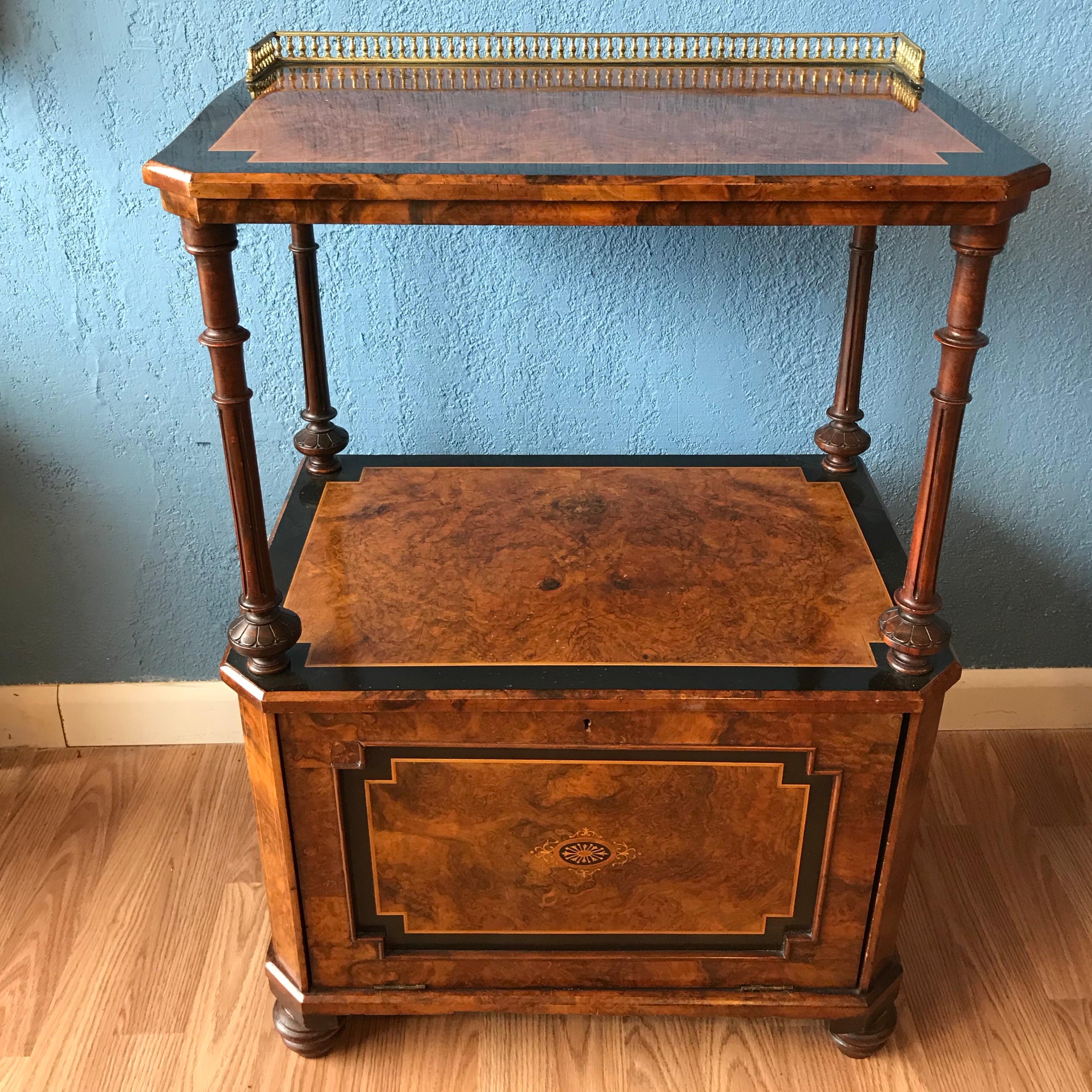 The table is beautifully designed with a burl wood top and shelf.
Its base is fashioned with a pull down compartment. 
The top is accented with a brass gallery.
Superb quality.