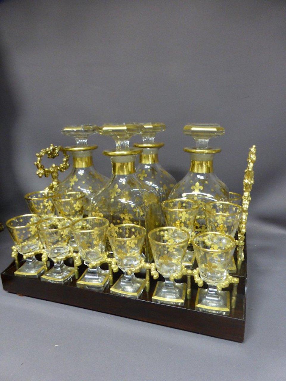 Belle cave à liqueurs en bois noirci d'époque Napoléon III comprenant un panier amovible avec trois carafes et douze verres dorés assortis décorés à l'or fin.
La boîte a un couvercle incurvé décoré d'un cartouche en son centre sur un entourage de